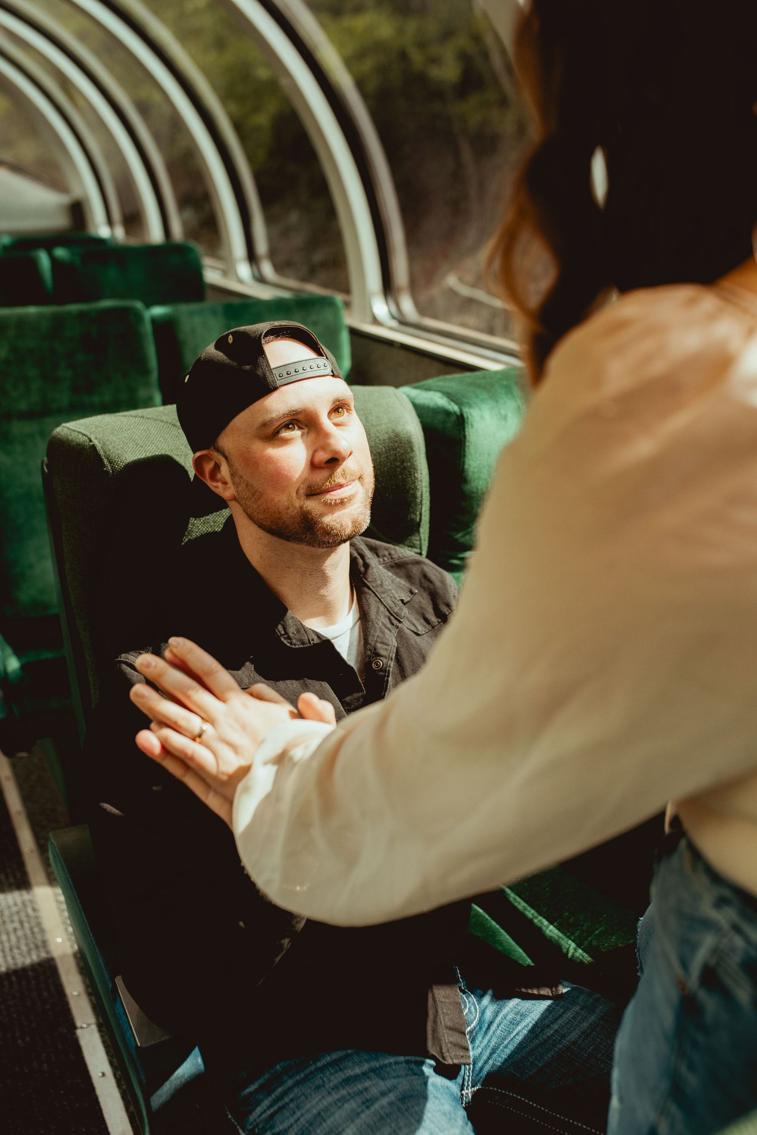 Couple sharing tender moment while seated in vintage train car.