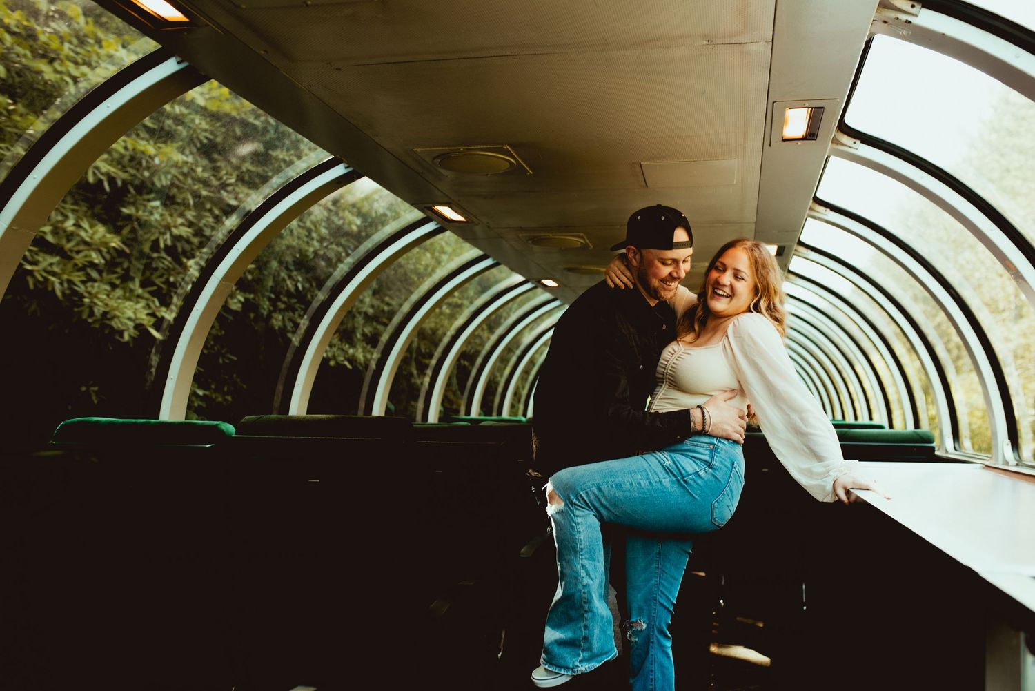 An intimate moment captured in the curved glass ceiling observation car of a vintage train.