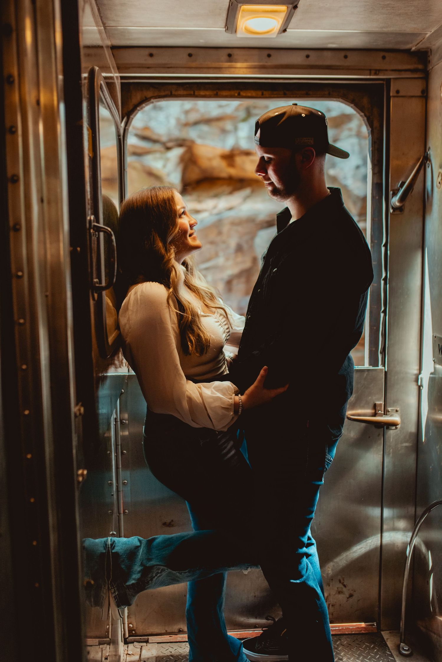 A romantic embrace captured in the moody lighting of a vintage train car interior.