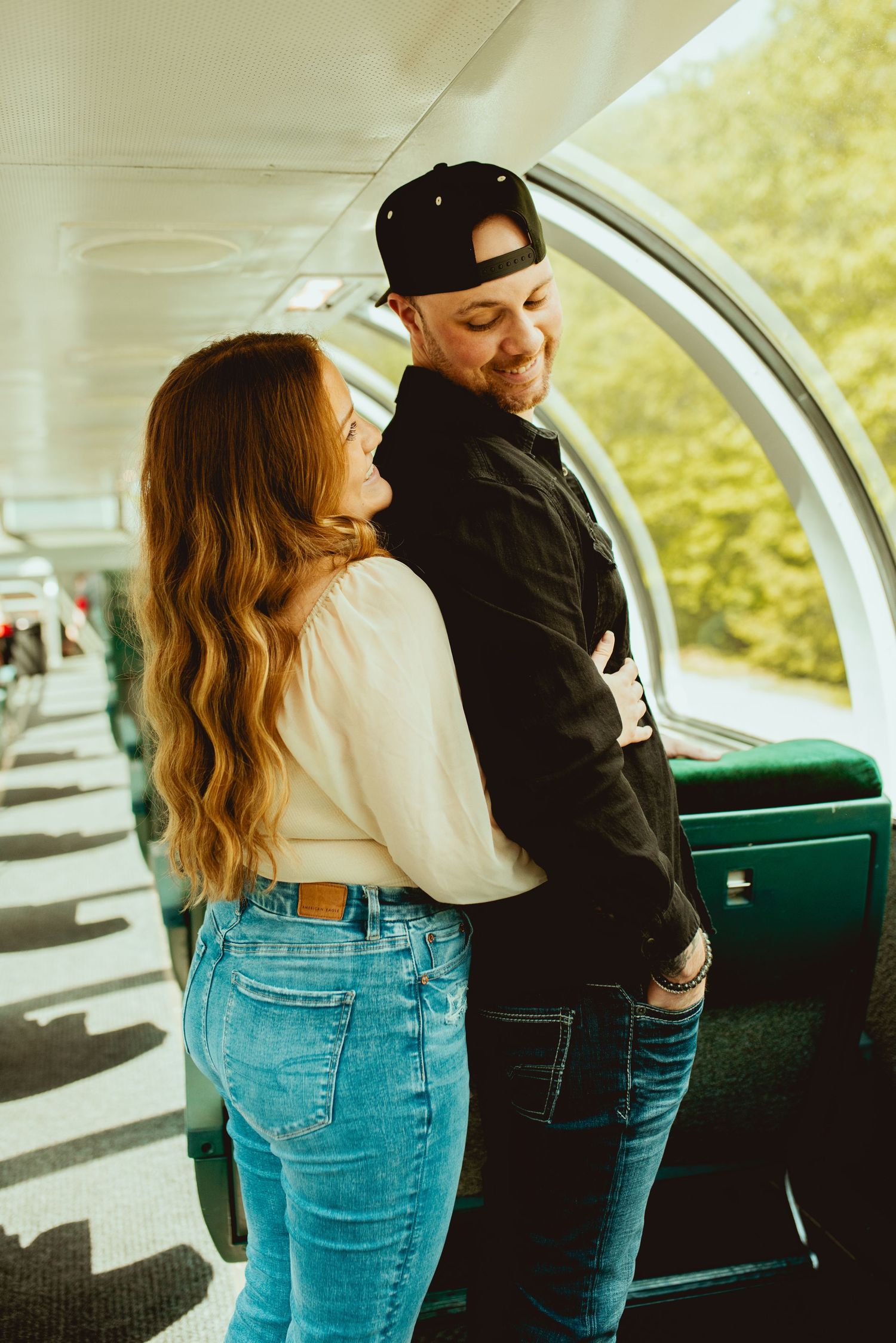 Casual couple in denim and casual wear sharing moment in train car interior.