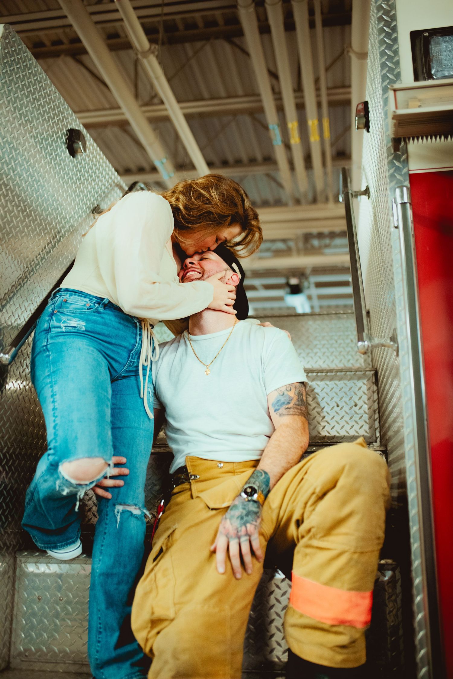 An intimate moment shared between two people on fire truck steps in the station.