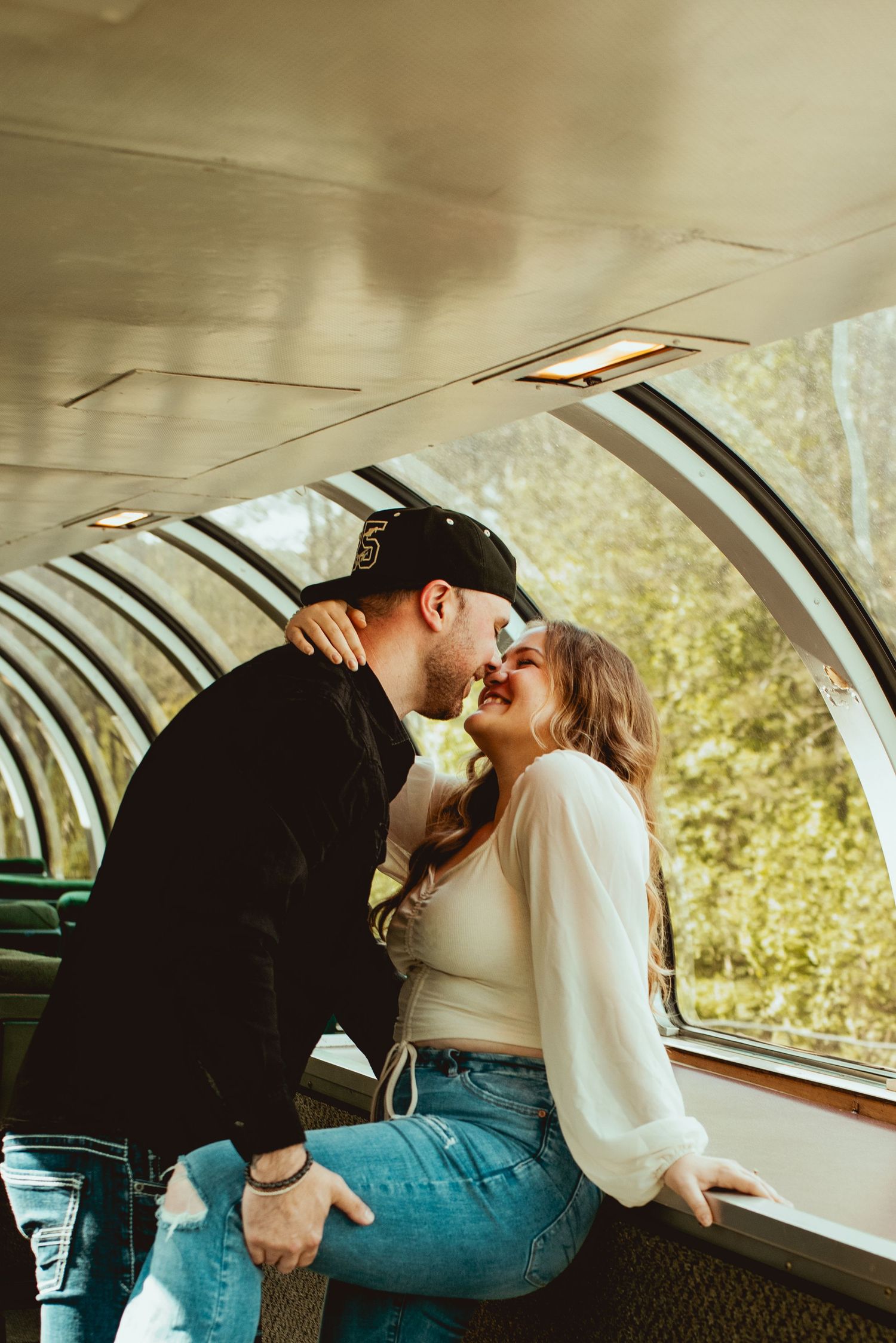 A romantic moment shared between a couple in a vintage train car with sunlit windows.