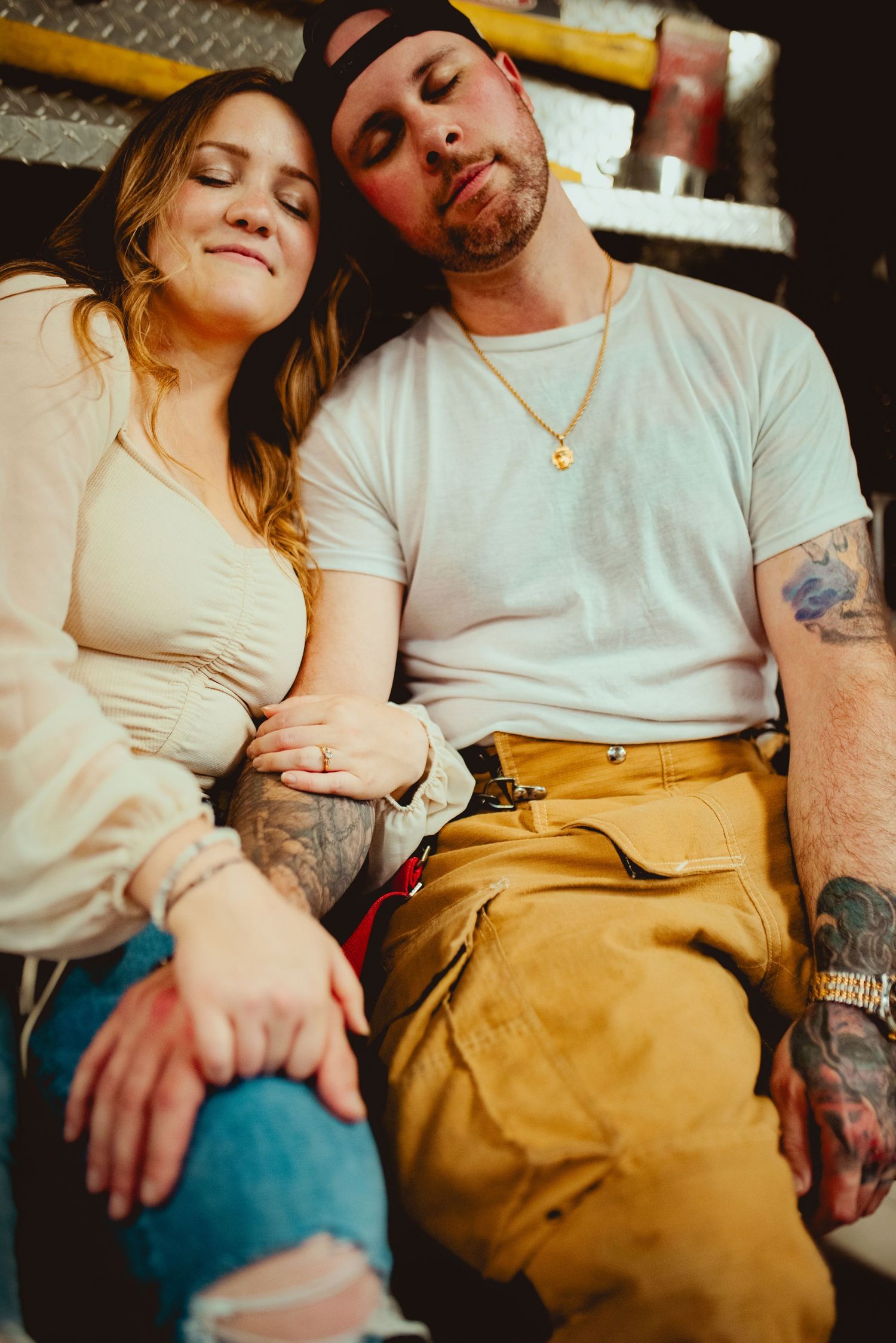 Couple in casual attire sharing intimate moment on fire truck.