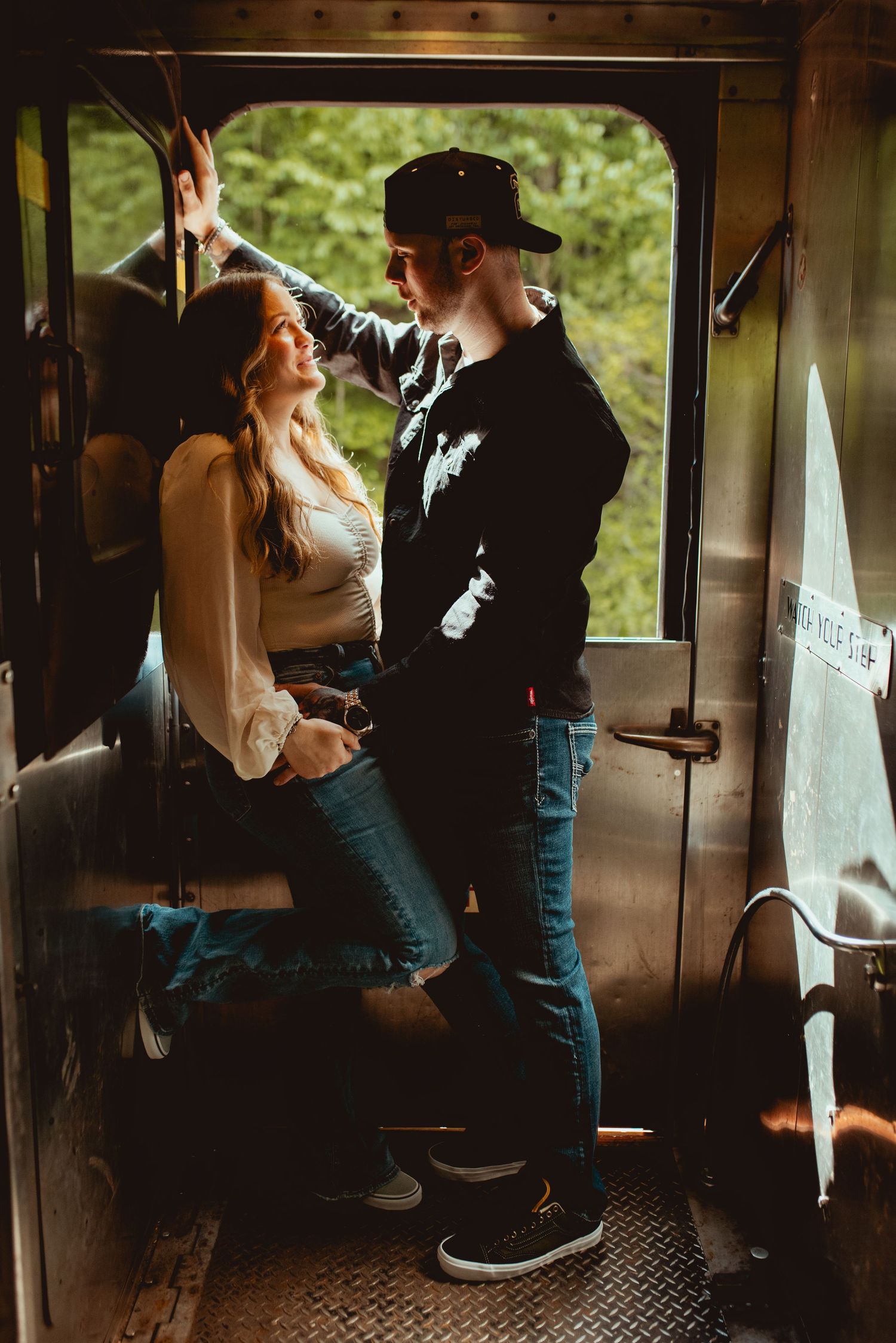 A romantic moment captured inside a vintage train car with dramatic lighting and shadows.