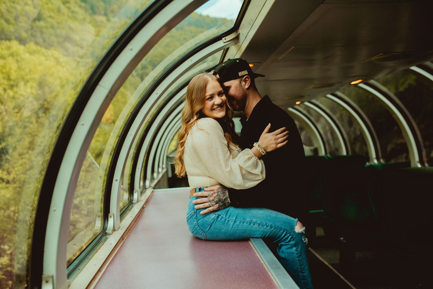 Couple sharing affectionate embrace by window in vintage train car.