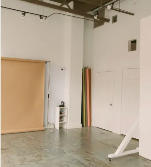 Photography studio interior with peach colored backdrop and white walls.