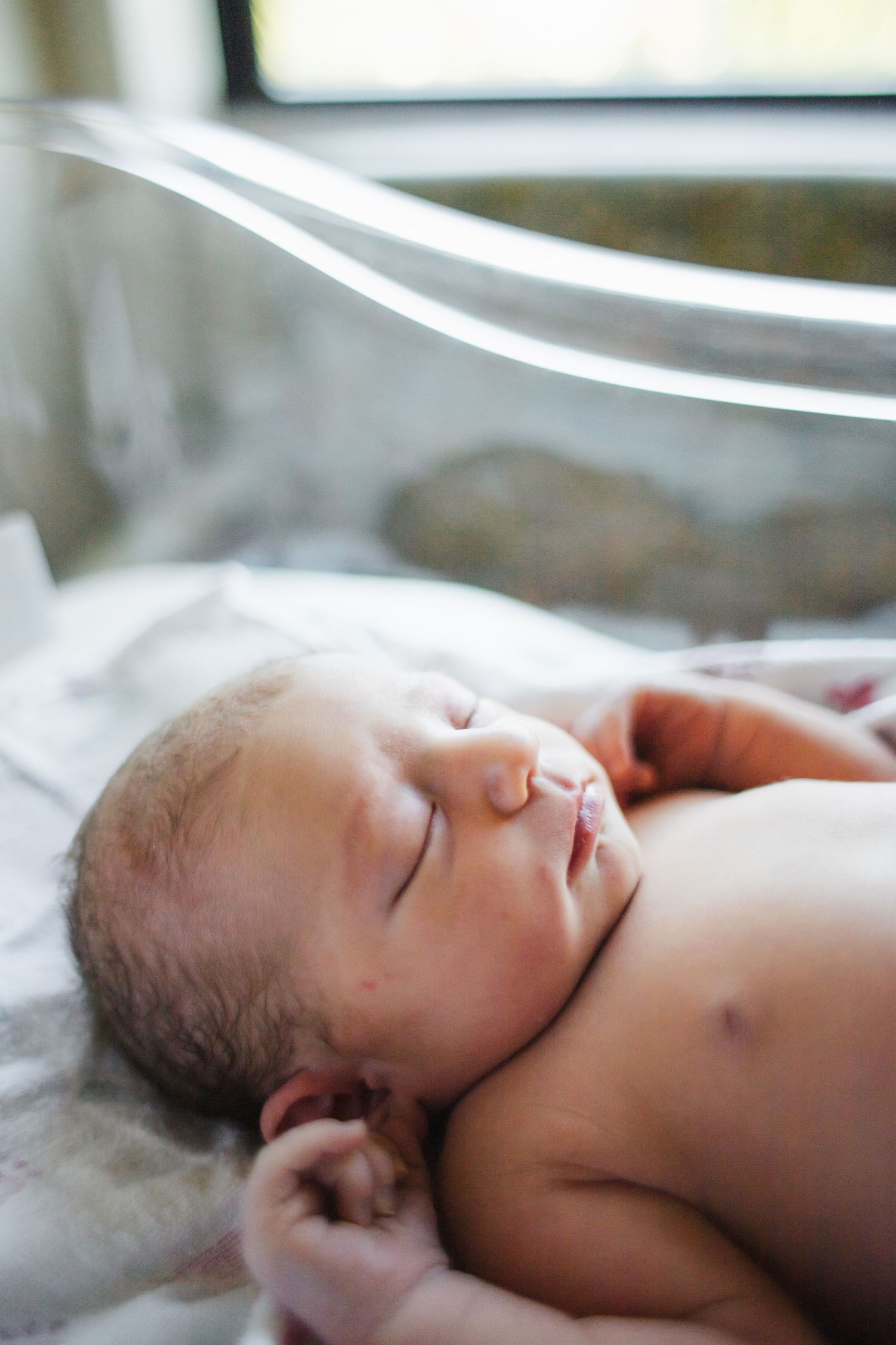 Peaceful sleeping newborn baby photographed in soft natural light.