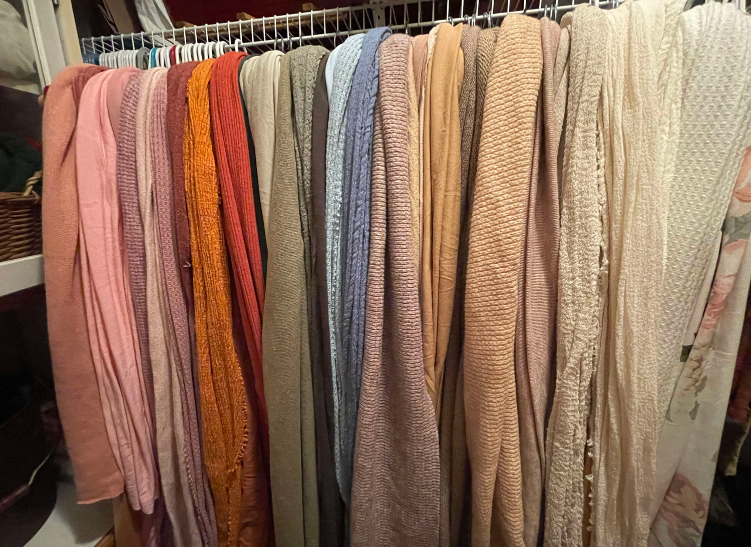 Collection of textured throw blankets in various neutral and warm colors hanging on display.