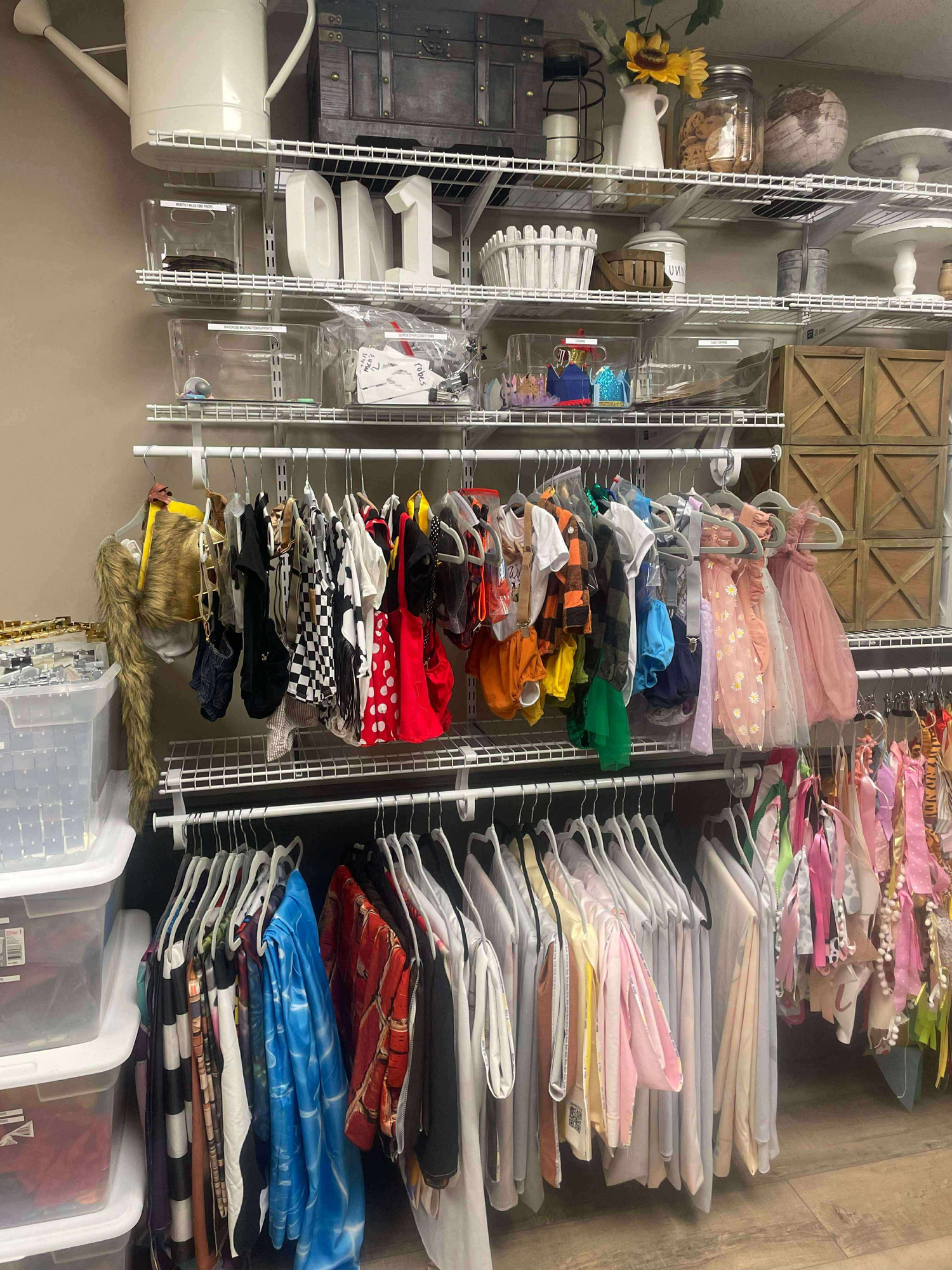 Organized retail storage area with clothing racks and shelves displaying colorful dresses and supplies.