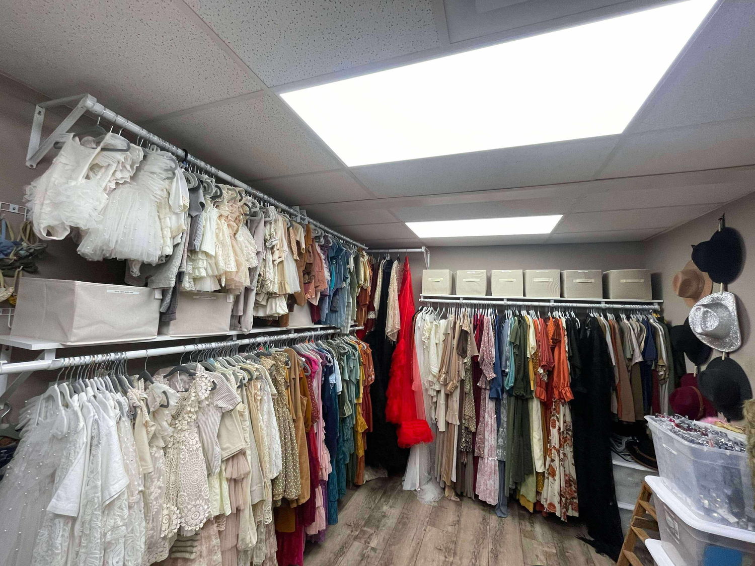 Organized clothing storage room with racks of apparel in different colors and styles.