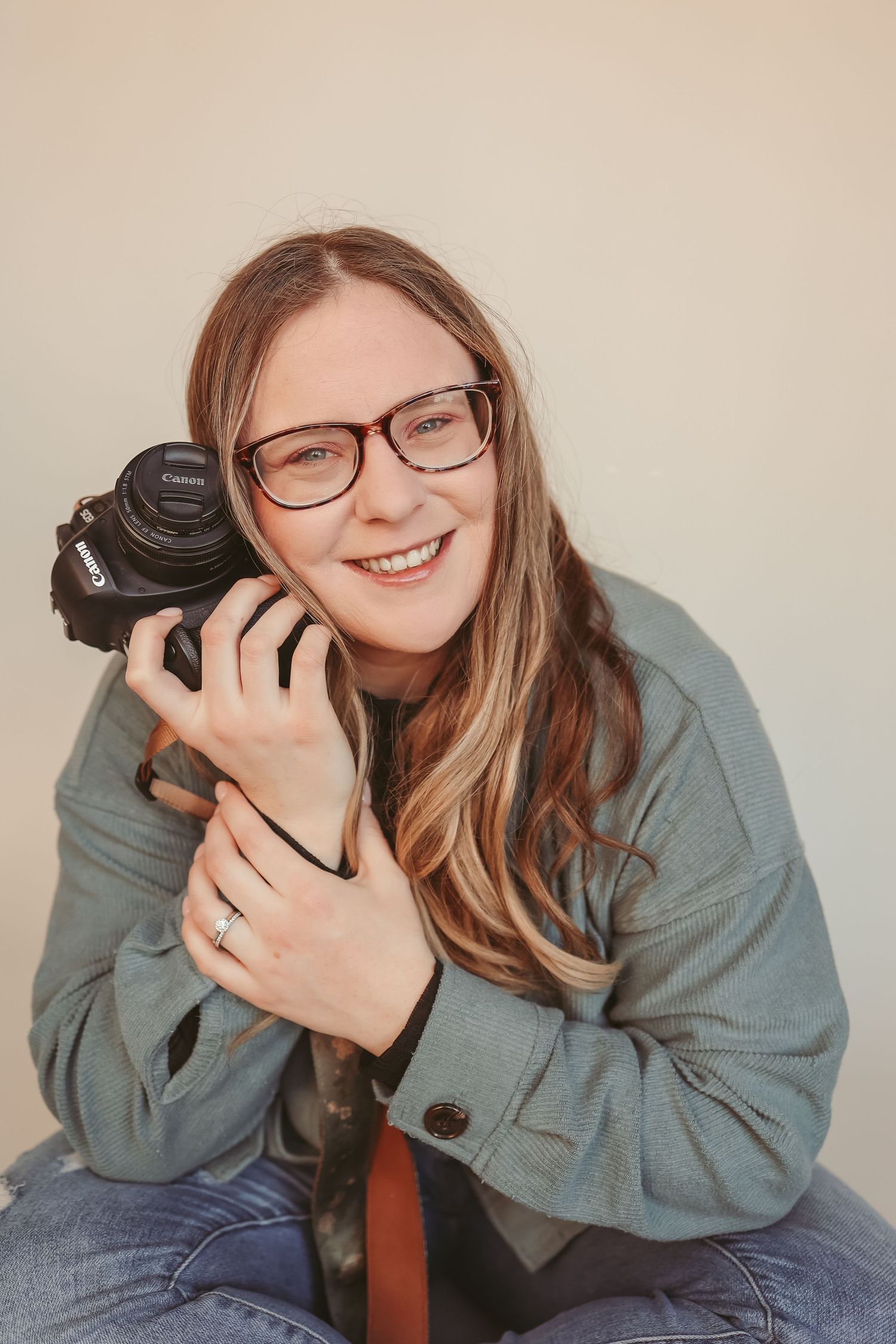 Kaitlyn, Springfield MO lifestyle family and newborn photographer, smiling with camera in natural light studio.