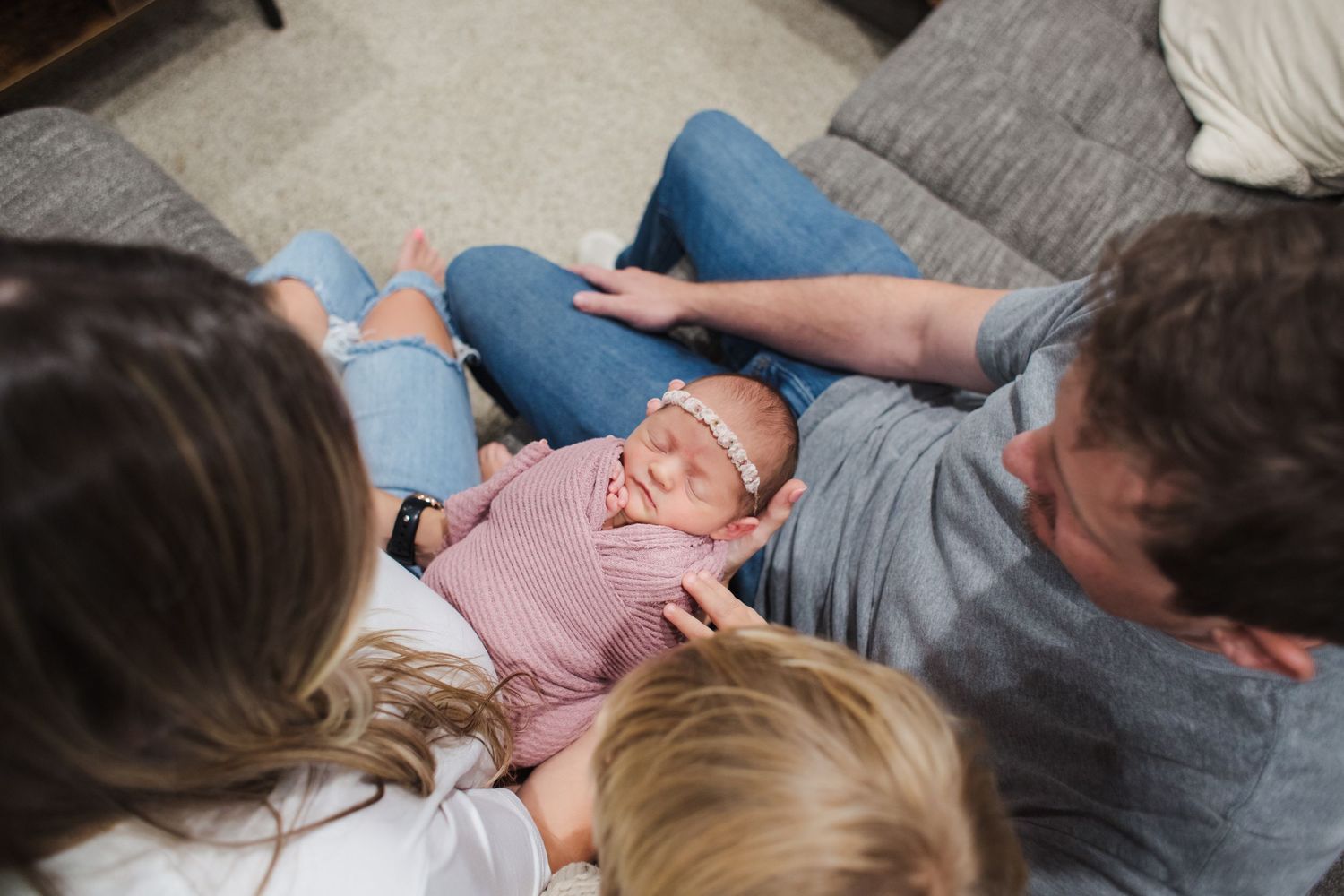 A peaceful moment with a baby lying between family members on a cozy sofa at home.