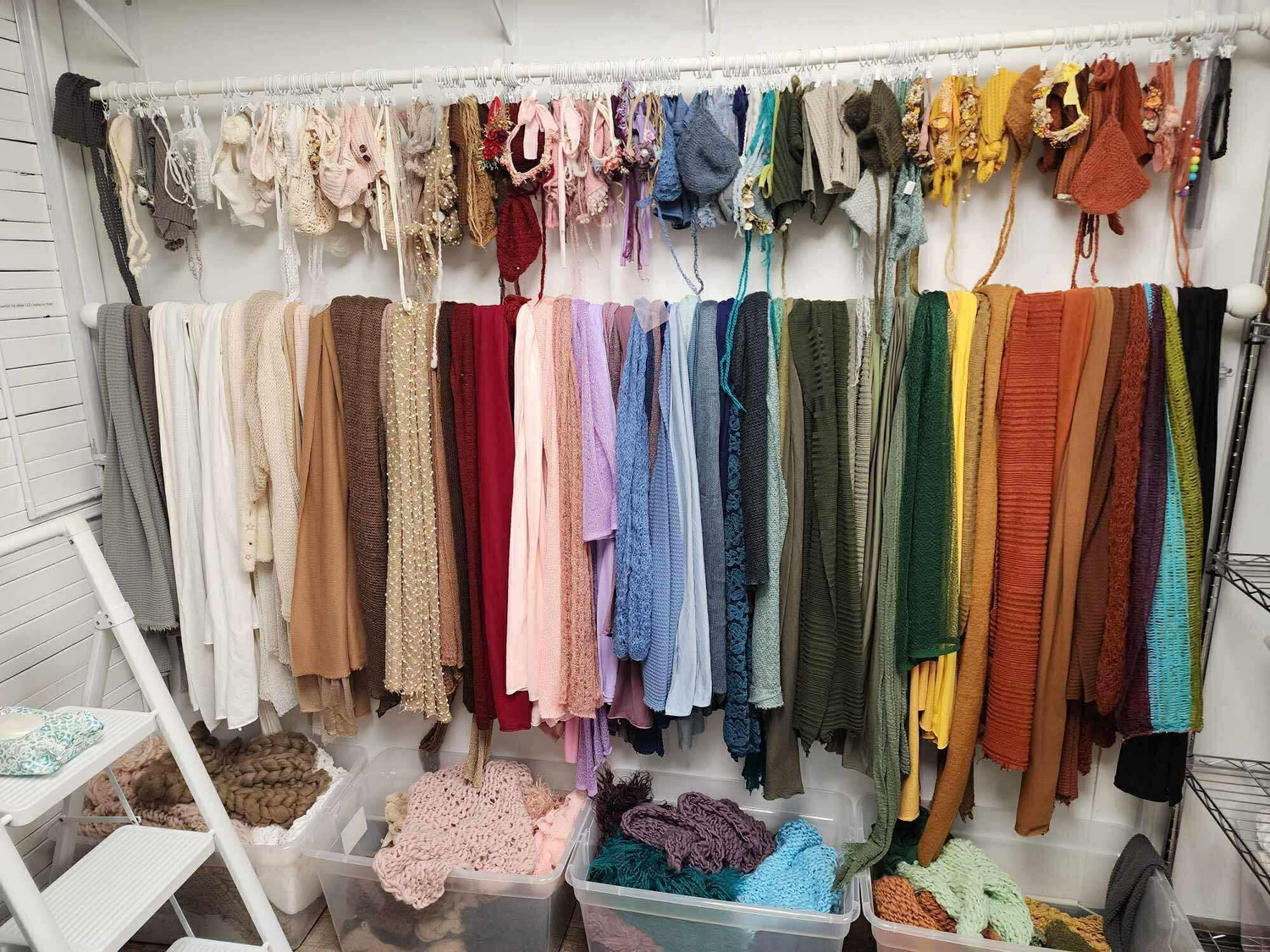 Clothing display with colorful garments neatly arranged on hanging racks against white walls.