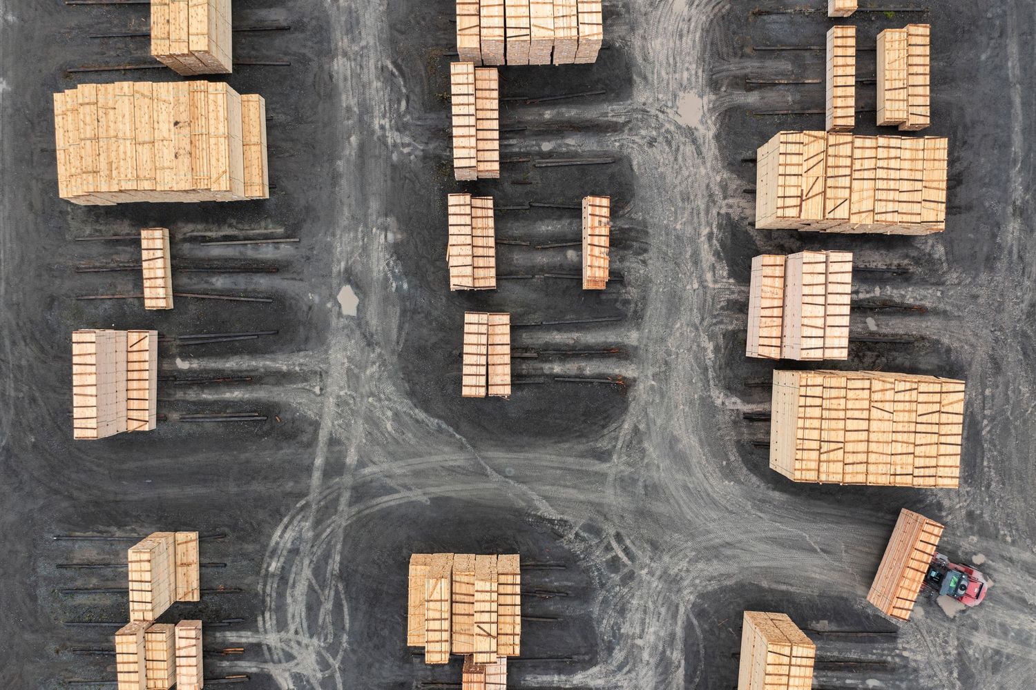 Bird's eye view of wooden storage containers arranged in rows on dark asphalt.