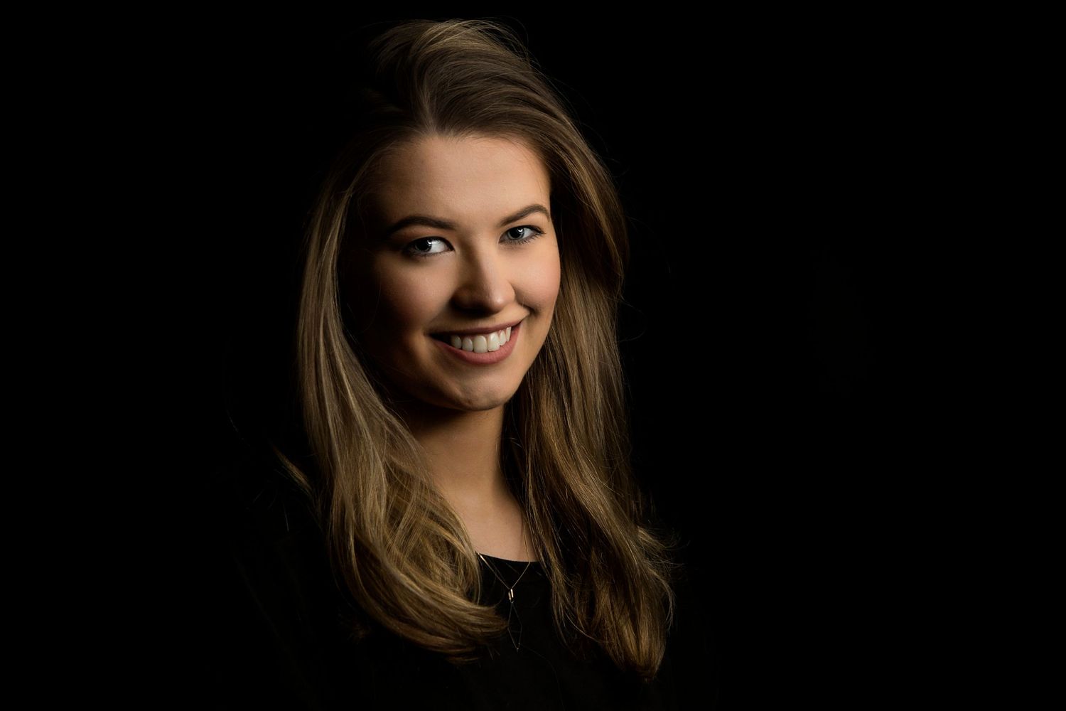 Dramatic low-key portrait series against black background showcasing warm lighting techniques.