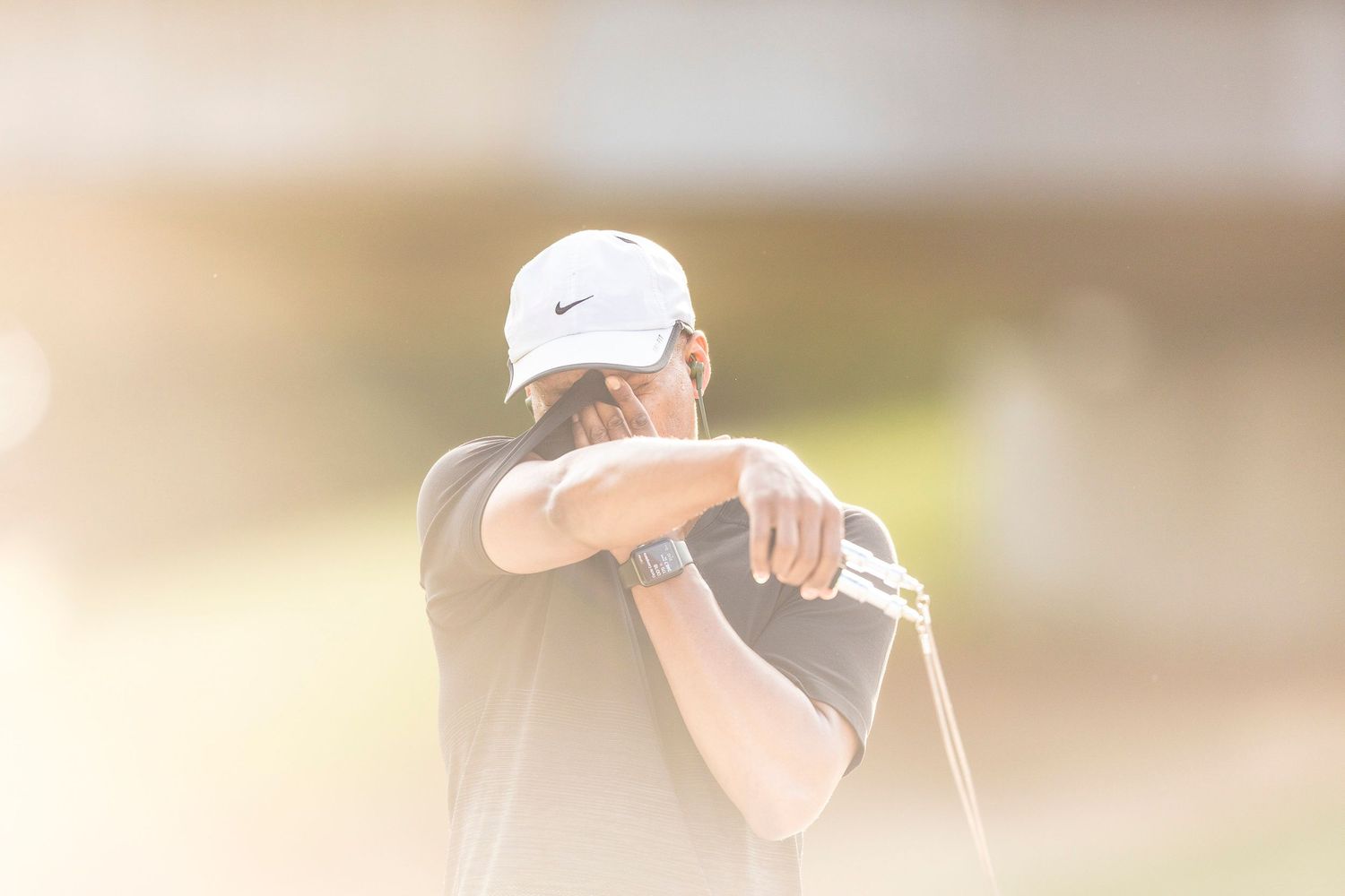 Athletic person practicing golf swings outdoors in bright sunlight.