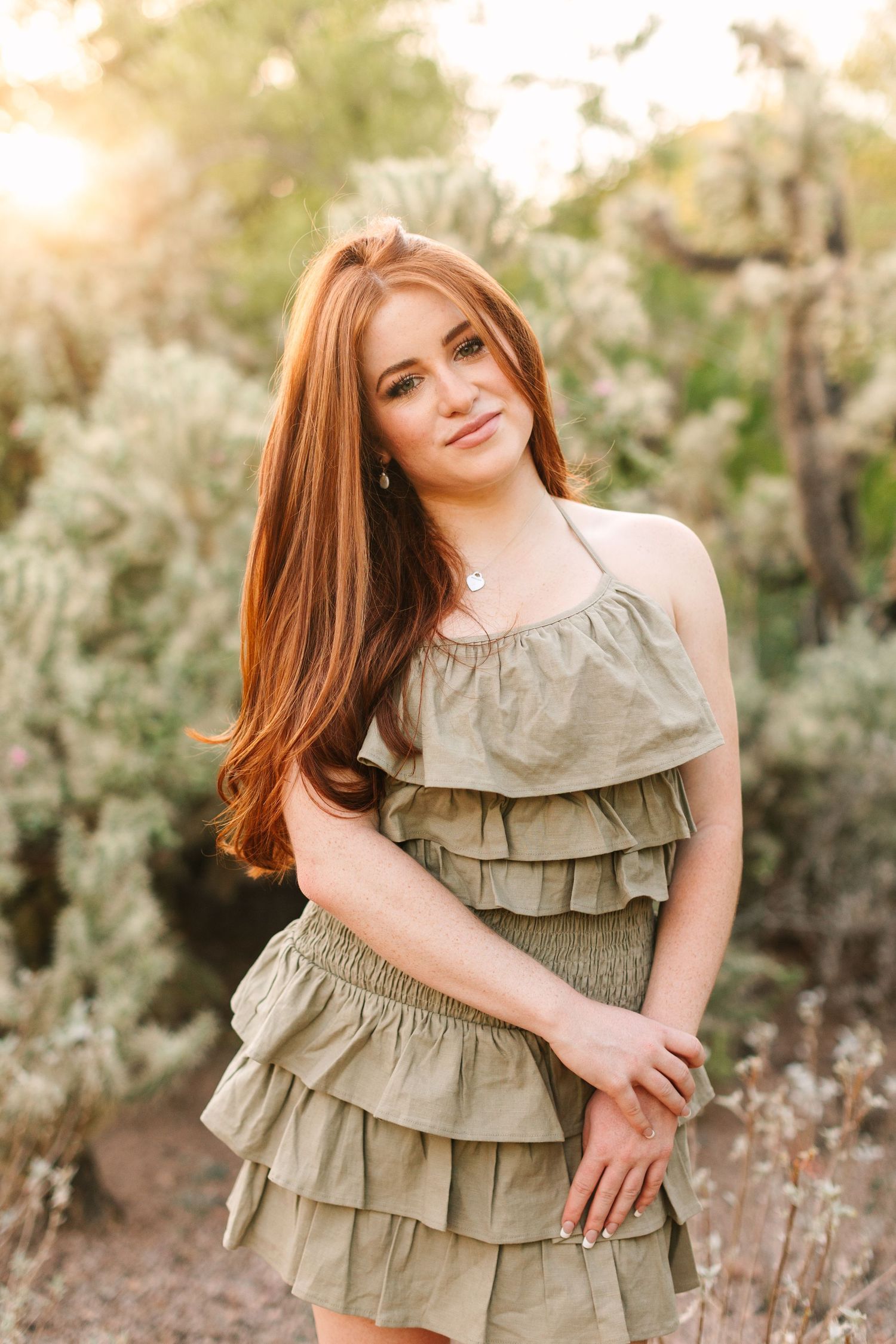 Portrait in nature wearing a sage green ruffled dress with gathered tiers against soft floral background.