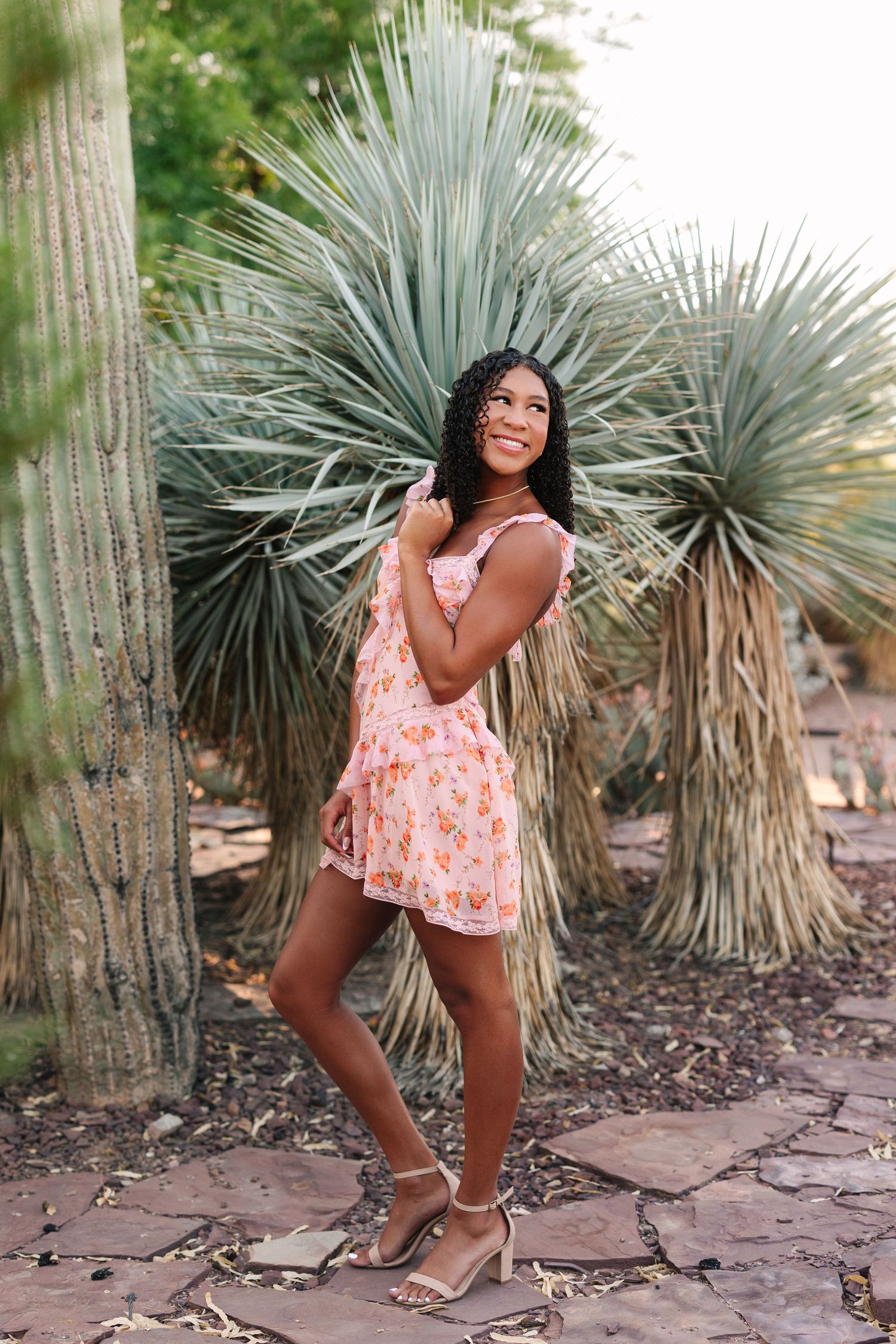 Beautiful floral sundress photographed in front of spiky desert plants and stone pathway in outdoor garden setting.