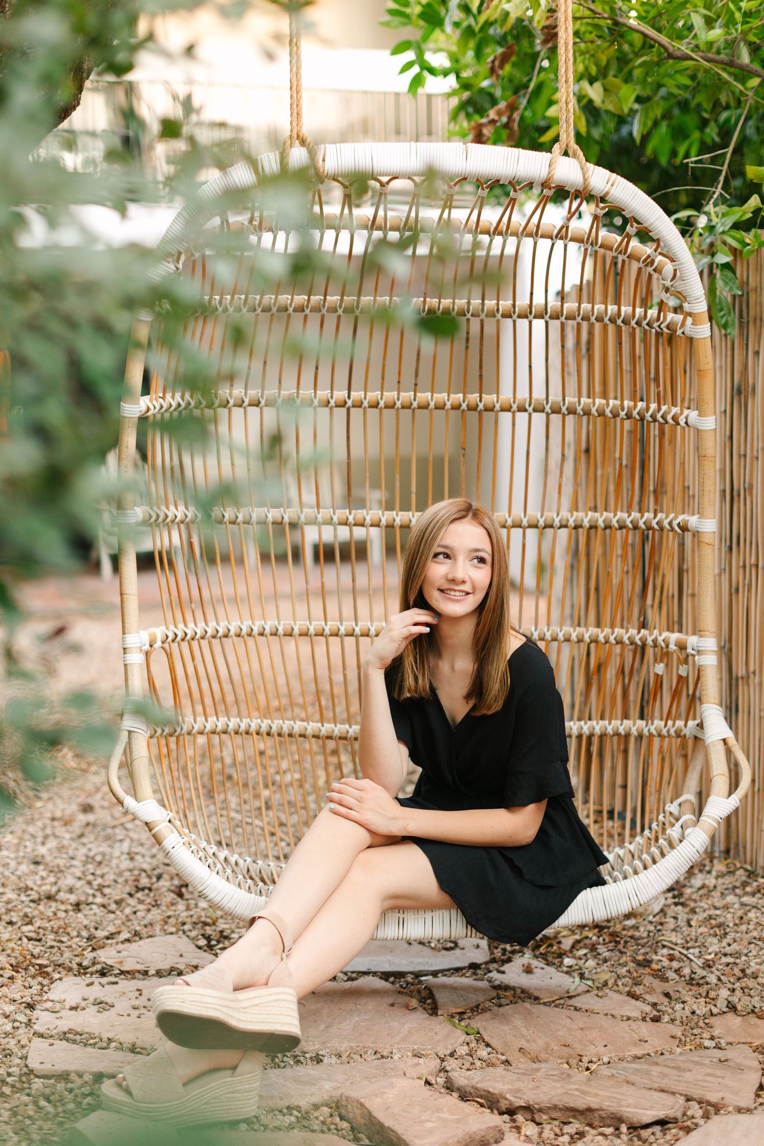 A hanging rattan egg chair in a garden setting creates a cozy outdoor seating spot.