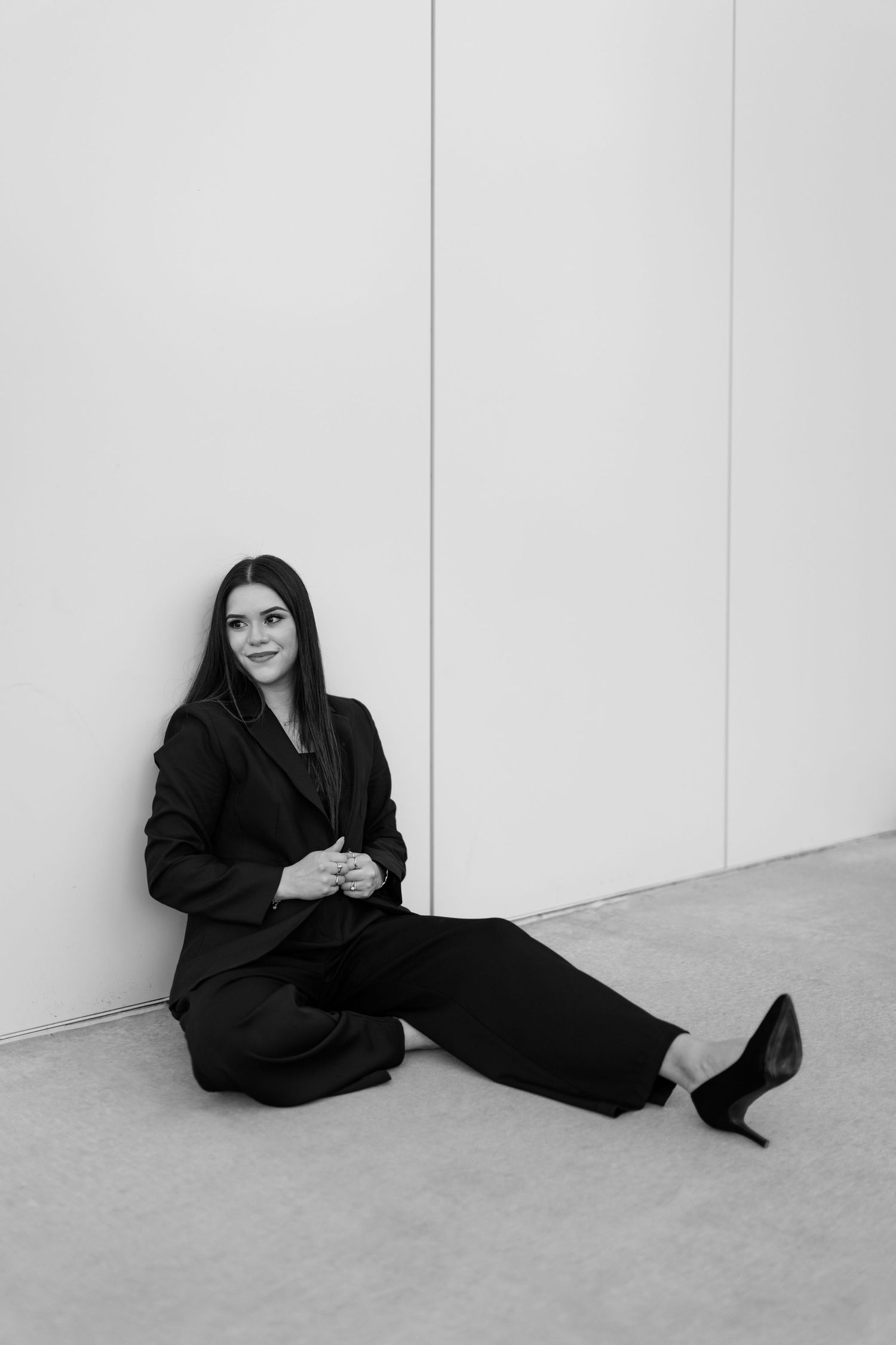 Black and white art portrait series shows a person in dark clothing reclining against a white wall in four sequential poses.