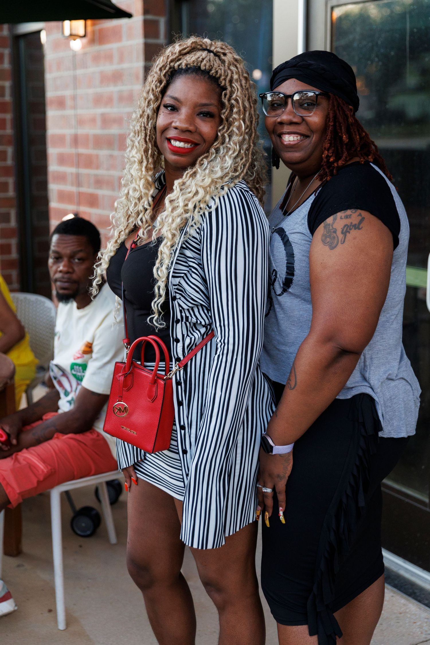 Two people in casual attire smile while posing together on an outdoor patio.