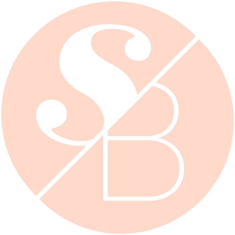 A minimalist circular logo design featuring elegant white S and B letters on a soft peach background.