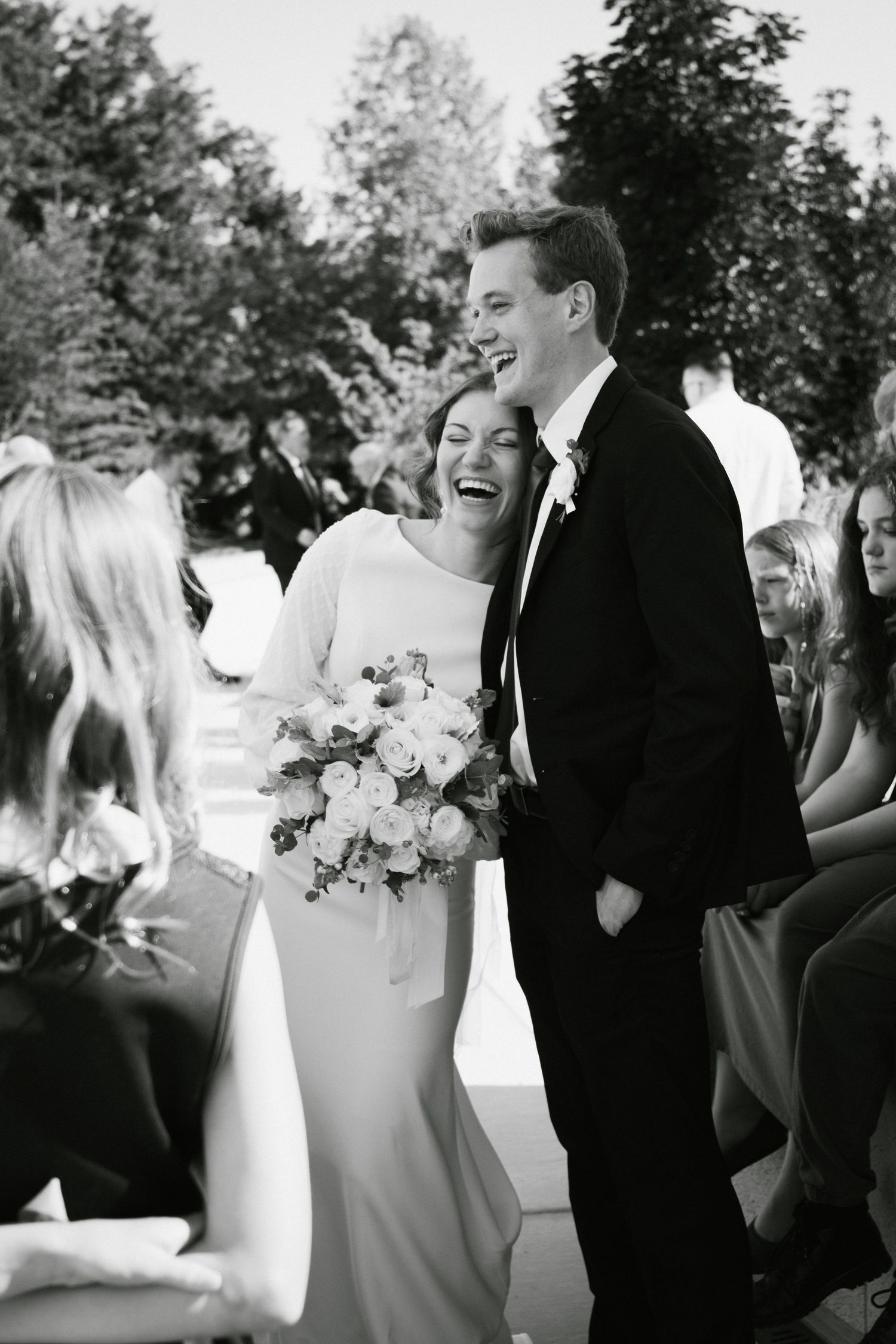 A couple sharing a joyful laugh together during their outdoor wedding ceremony.