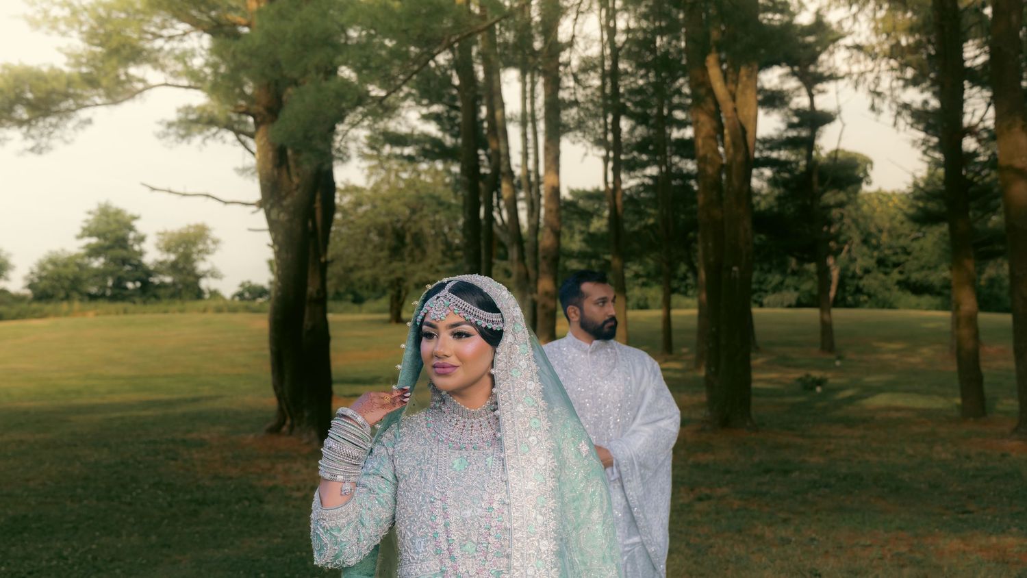 A romantic outdoor photoshoot in a sun-dappled wooded area with soft golden lighting.