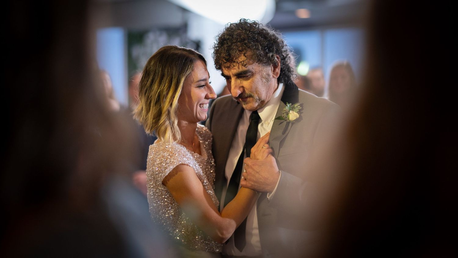 A close-up shot of a couple having their first dance at a wedding reception through a blurred vignette frame.