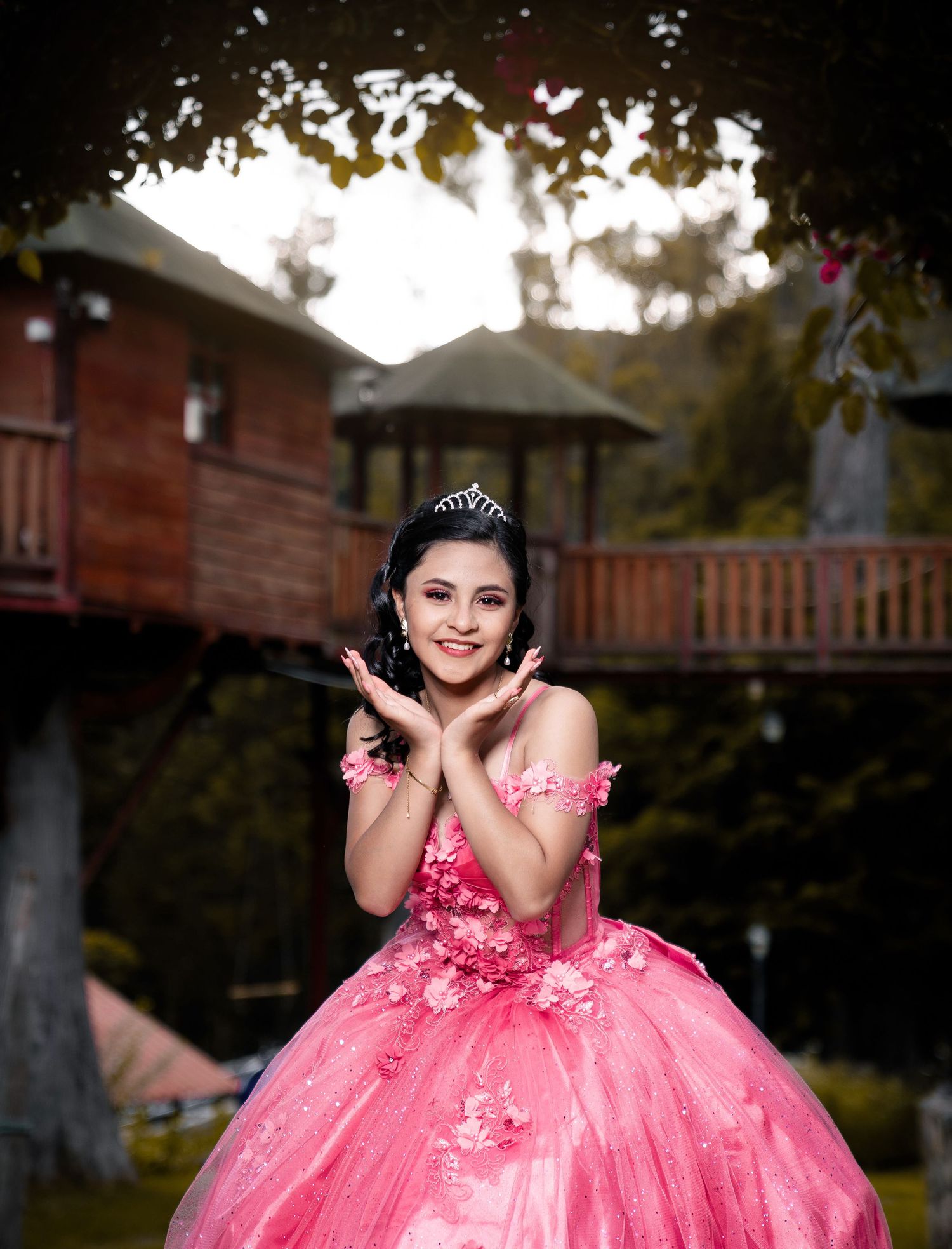 Young woman twirls in a pink floral quinceañera gown during an outdoor photoshoot.