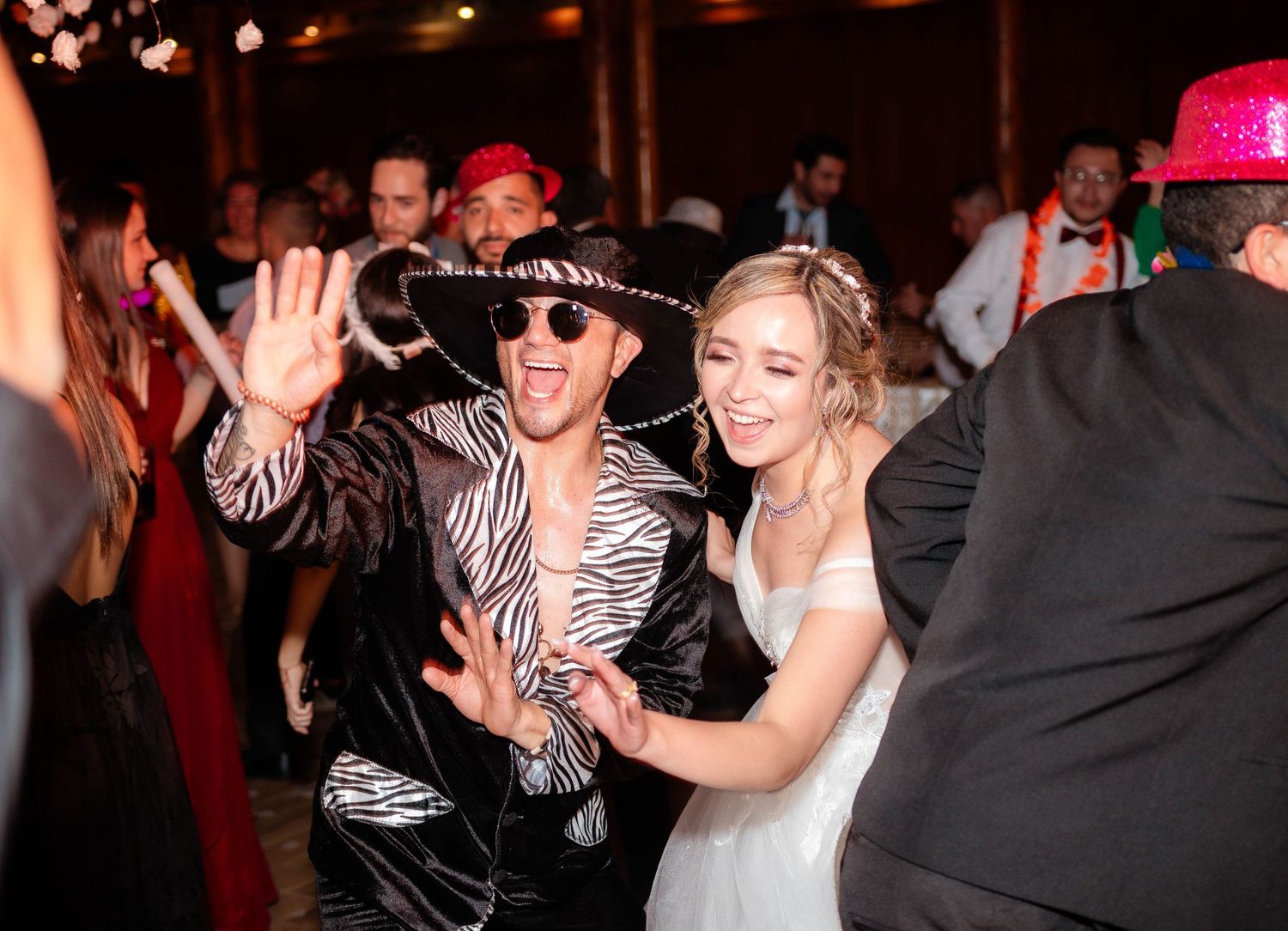 A group of people dance and celebrate during an energetic party with dimmed lighting and festive atmosphere.