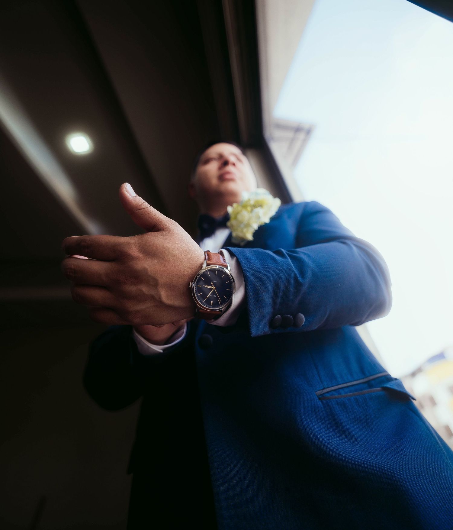 Low angle photo showing someone in a blue suit jacket gesturing with their hand while wearing a wristwatch.