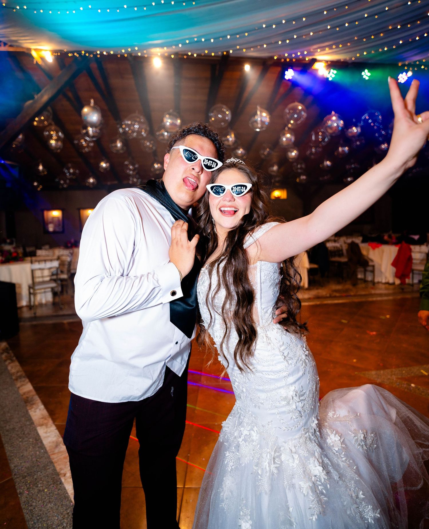 Celebratory moment at wedding reception with festive string lights and fun props.