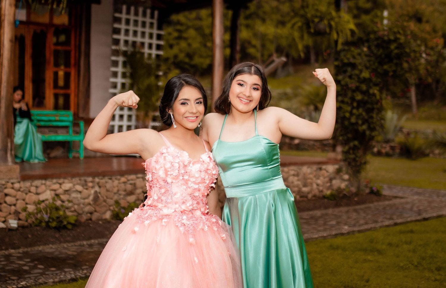 Celebration group photo with teal dresses and pink gown in garden setting.
