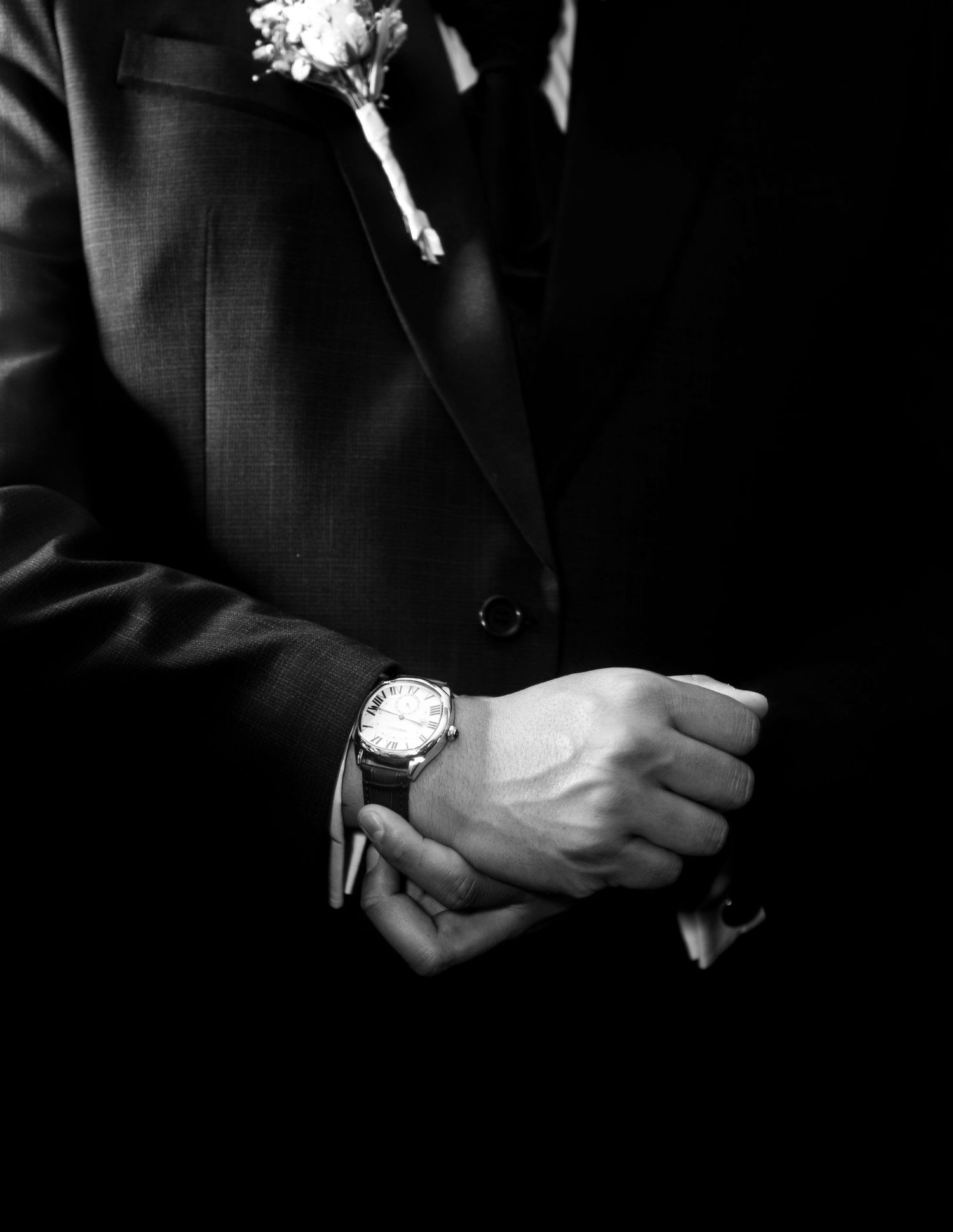 Close-up of groom's wrist watch and suit in classic black and white.