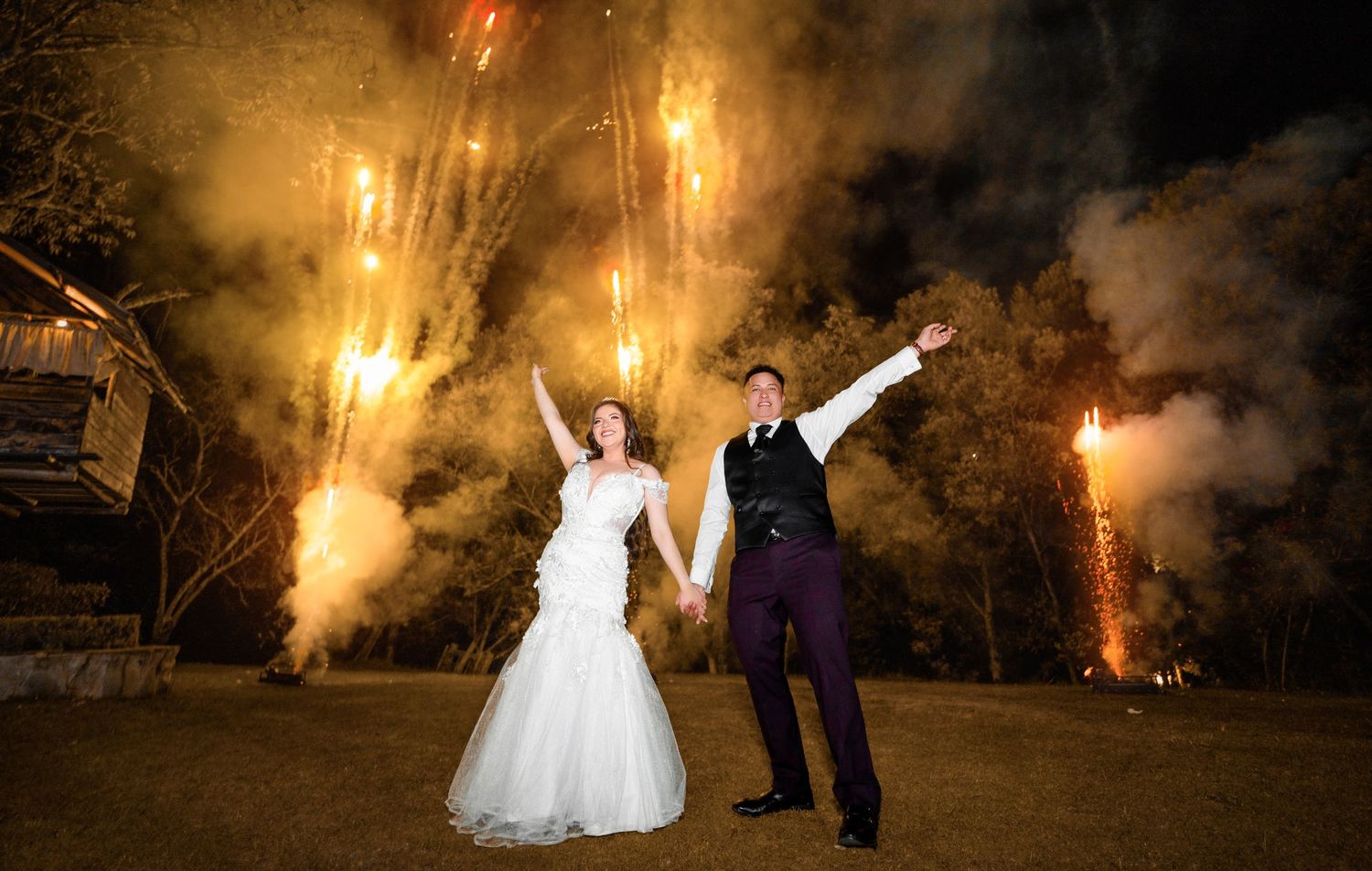 Newlyweds celebrate with dramatic fireworks display in night sky.