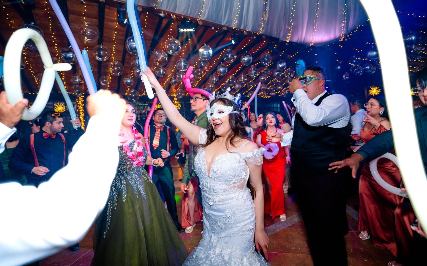 A celebration scene from a wedding reception with decorative white arches and dancing guests.