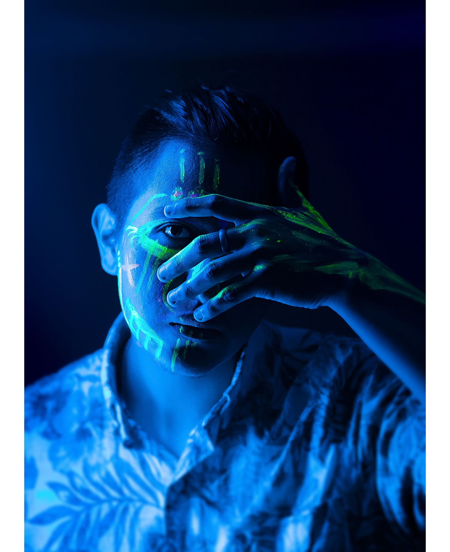 Artistic portrait with blue lighting and silhouetted hands covering a face.