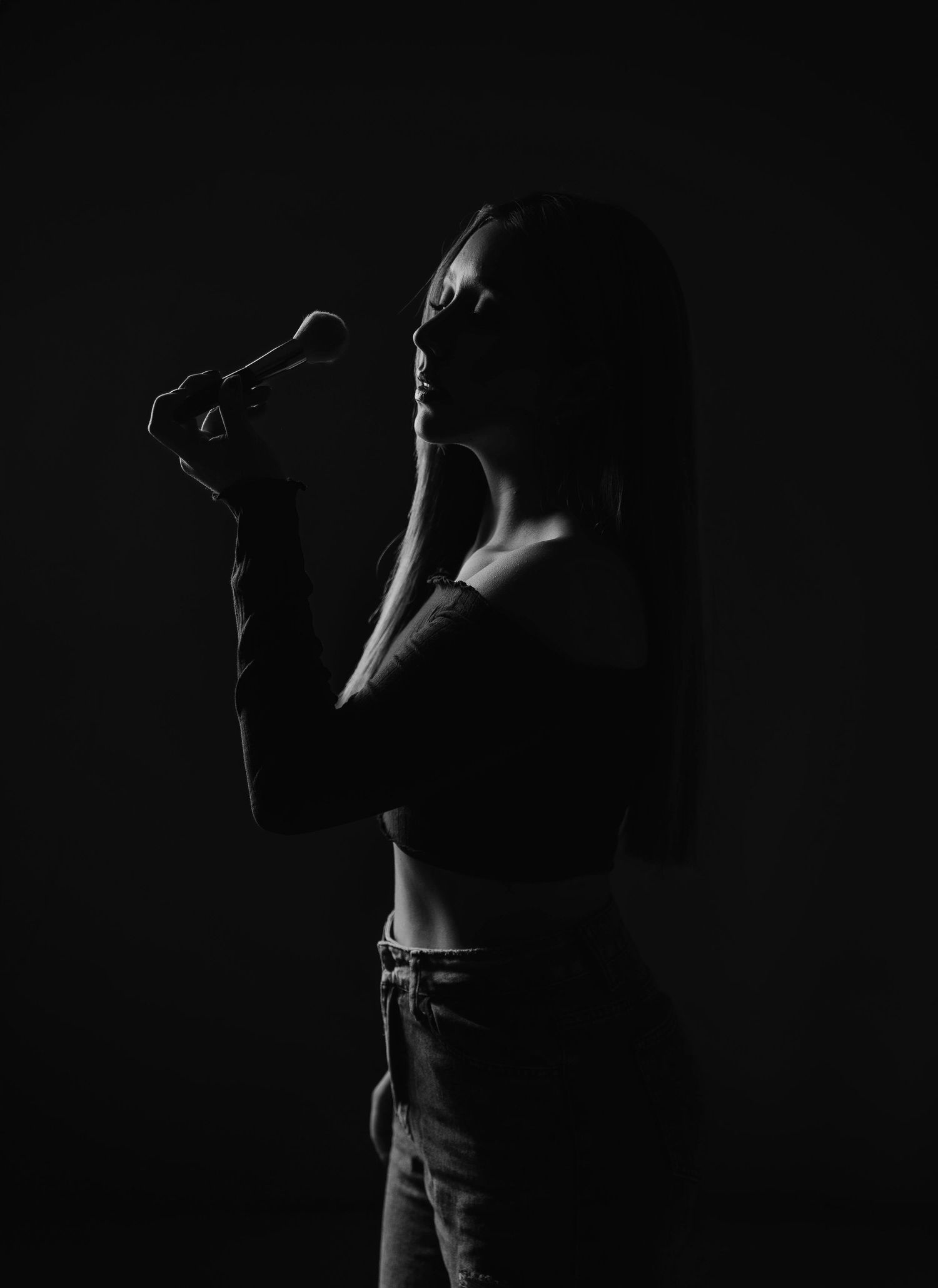 Dramatic black and white silhouette of a performer in shadow holding microphone against dark background.