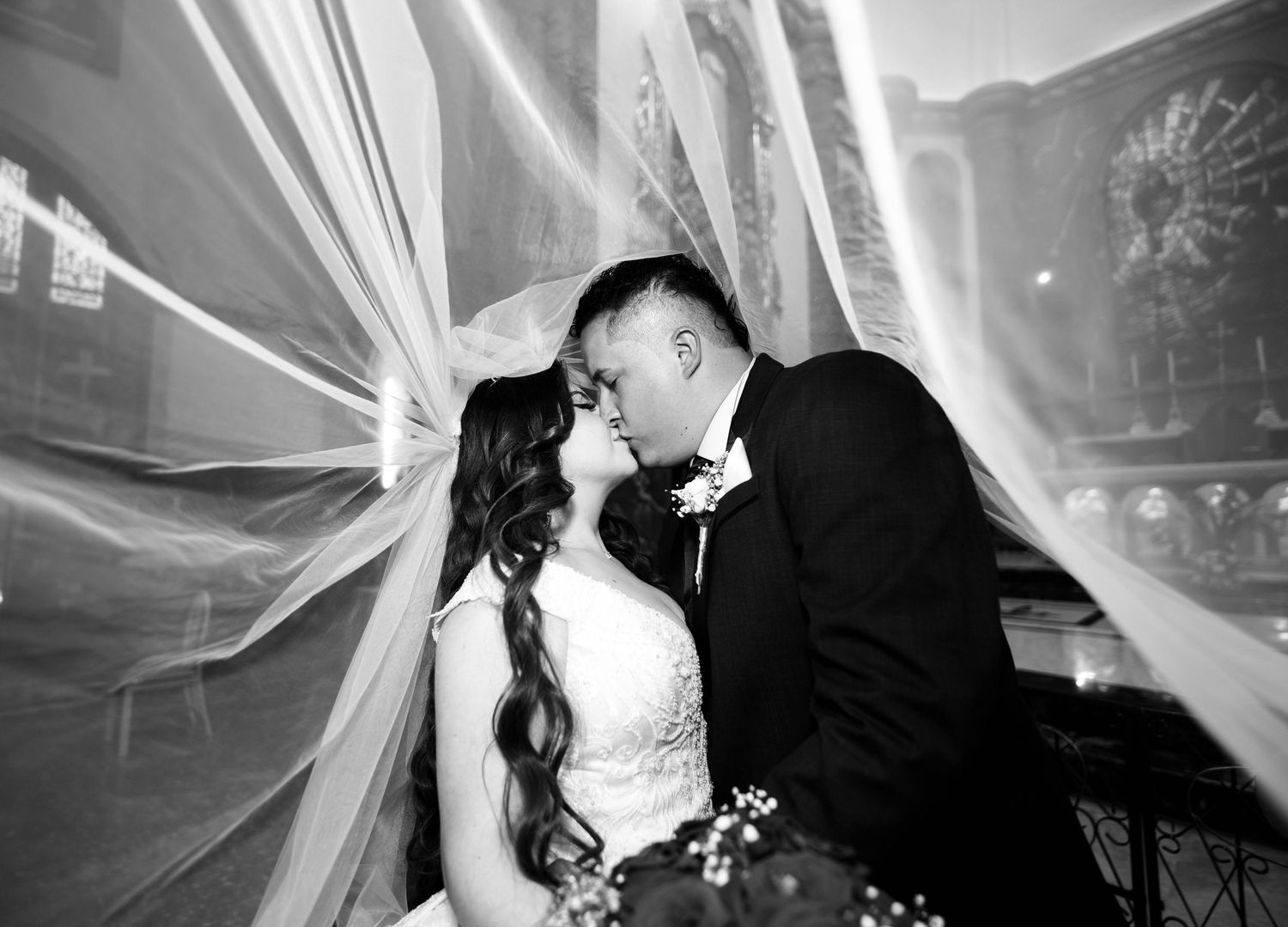 Romantic wedding portrait through flowing veil in black and white.