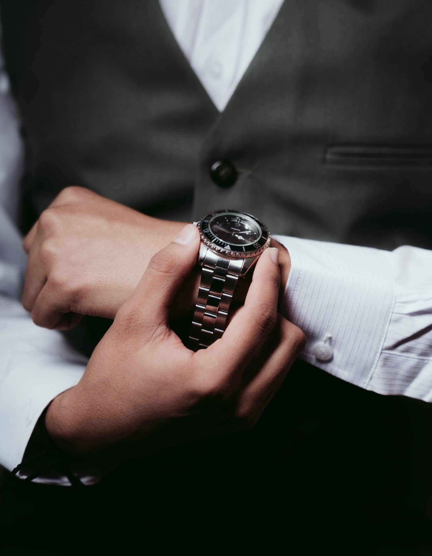 A series of close-up shots showing hands adjusting the sleeve and watch of a formal black suit.