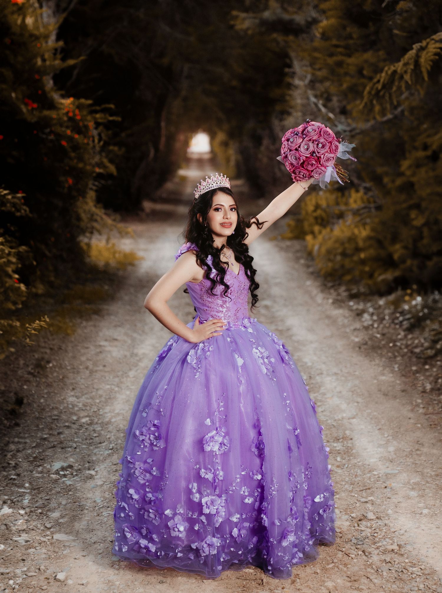 Purple princess ball gown with floral appliques photographed on rustic outdoor path.