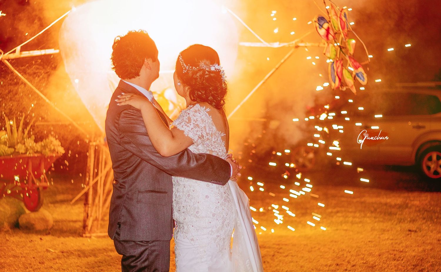 Couple embraces during sunset with magical sparkler effects.