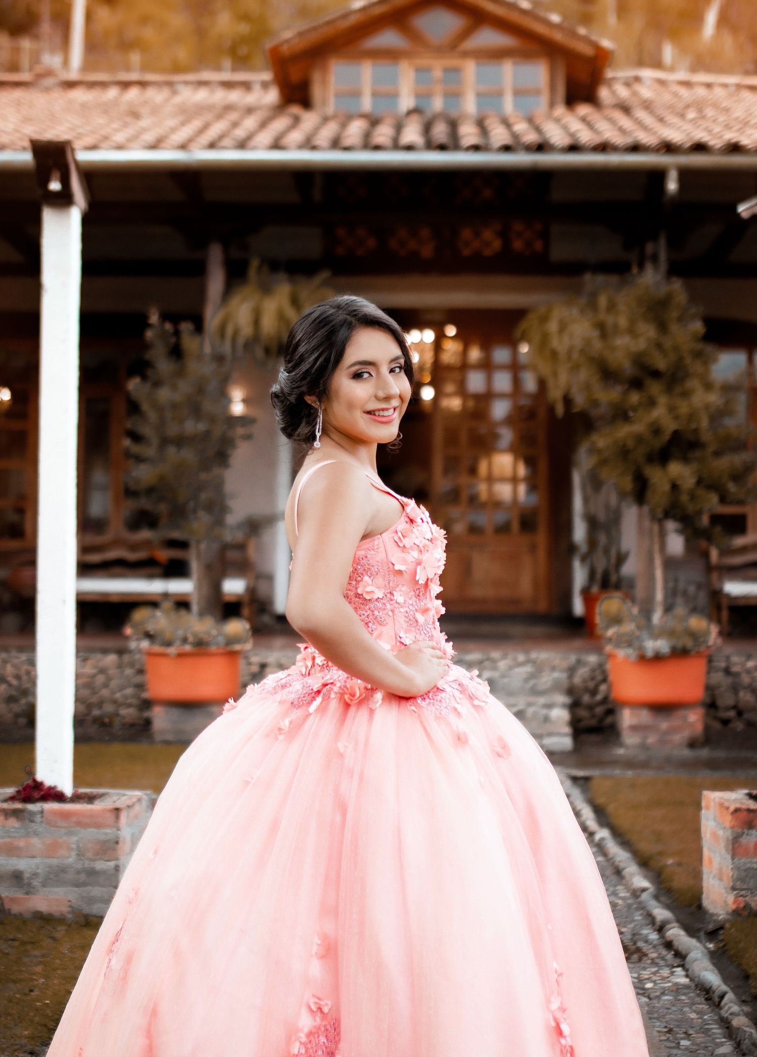 Elegant pink quinceañera gown photographed at rustic stone venue.