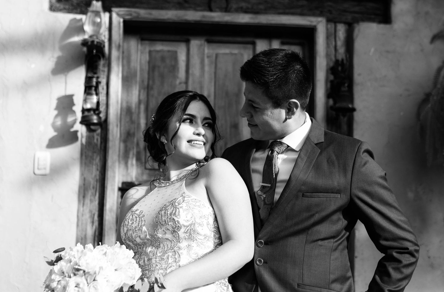A black and white wedding photo showing a happy couple sharing an intimate moment in formal attire.