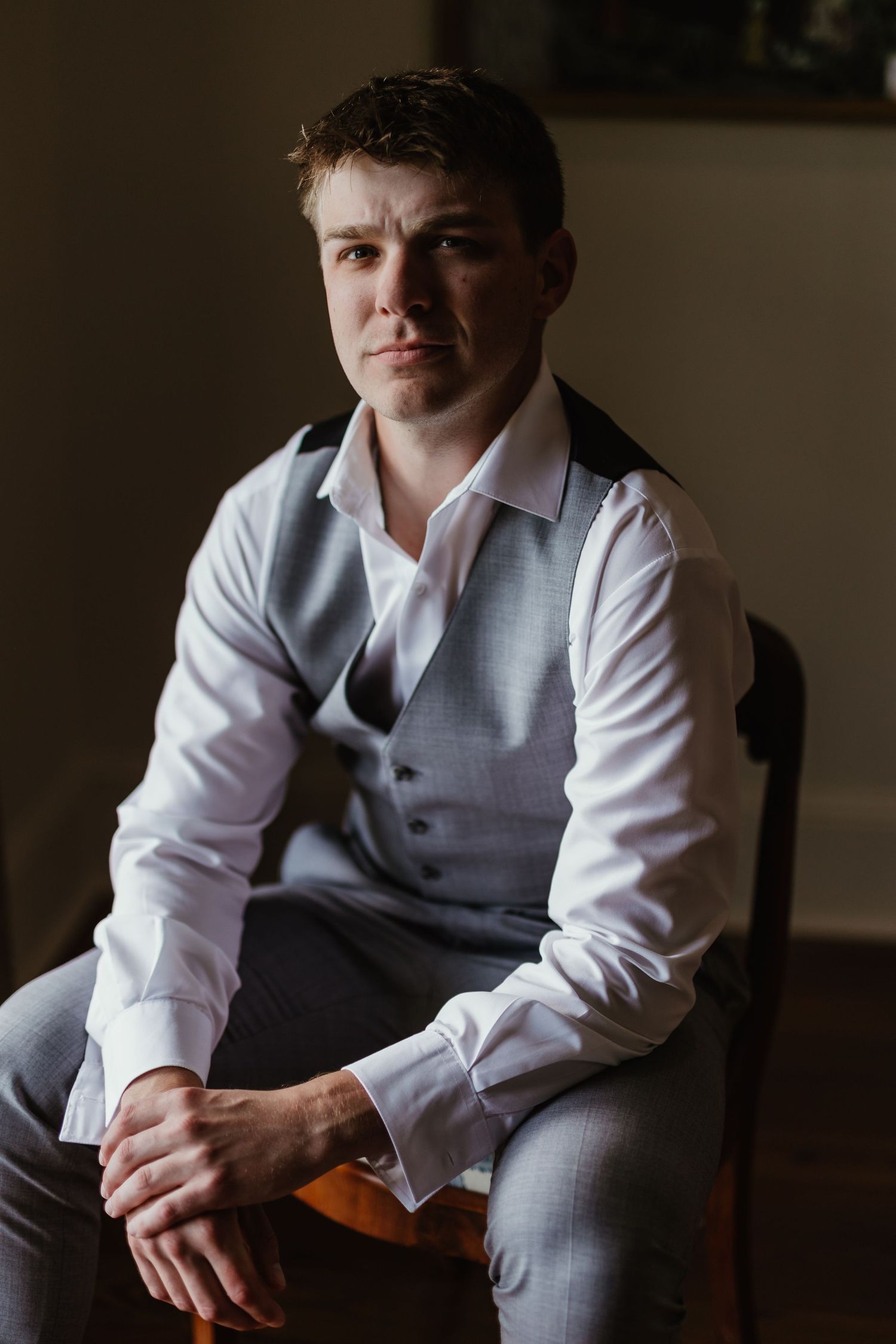 Professional portrait of someone sitting in formal attire featuring a light colored dress shirt and gray vest.