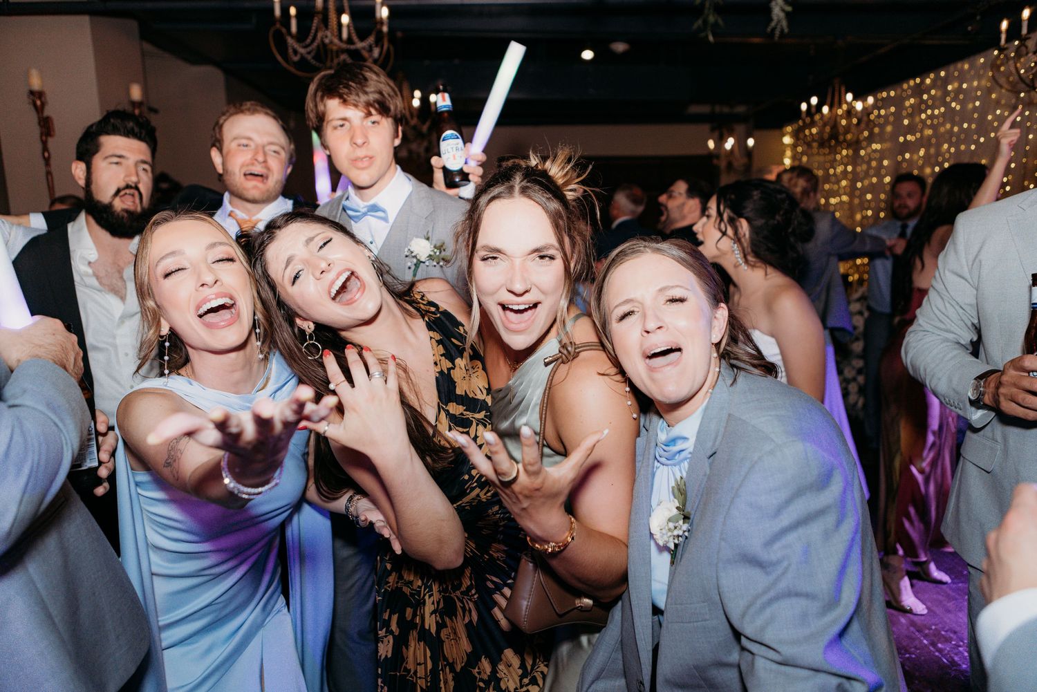 Group of wedding guests laughing and posing together for fun photo during reception party.