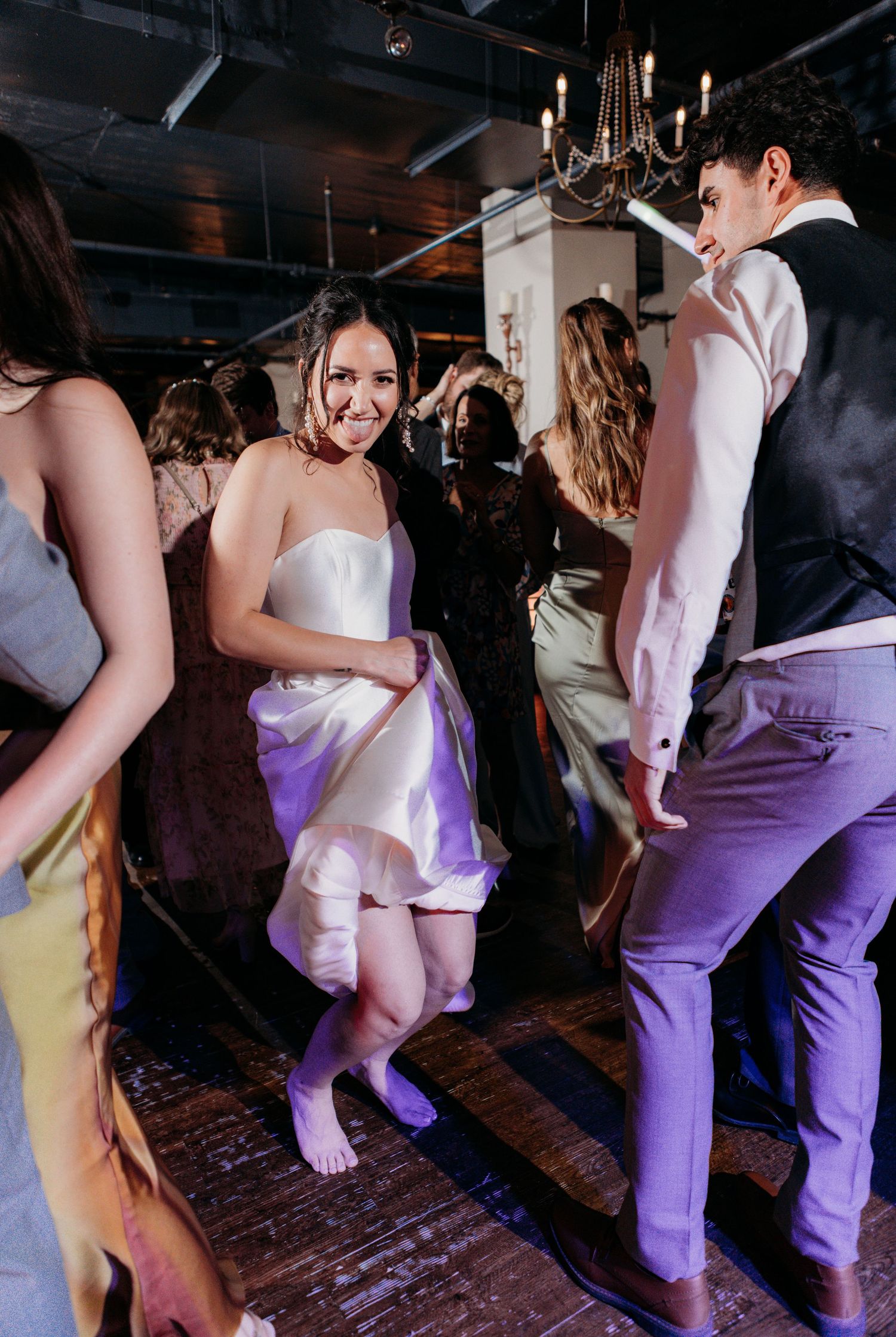 Wedding reception dance party with guests dancing and celebrating on a wooden floor.