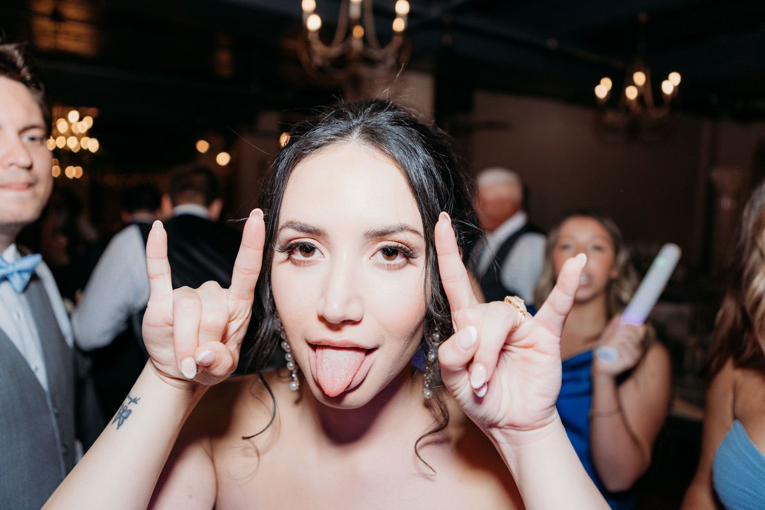 Guest making playful rock and roll hand gestures while enjoying wedding reception festivities.