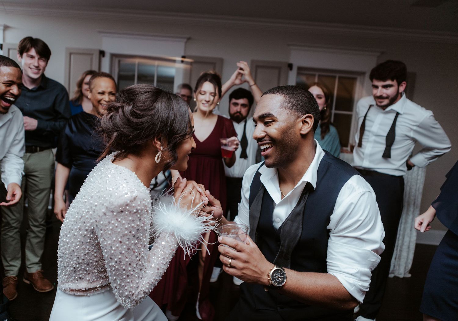 Joyful wedding reception scene with guests celebrating and dancing together at an indoor venue.